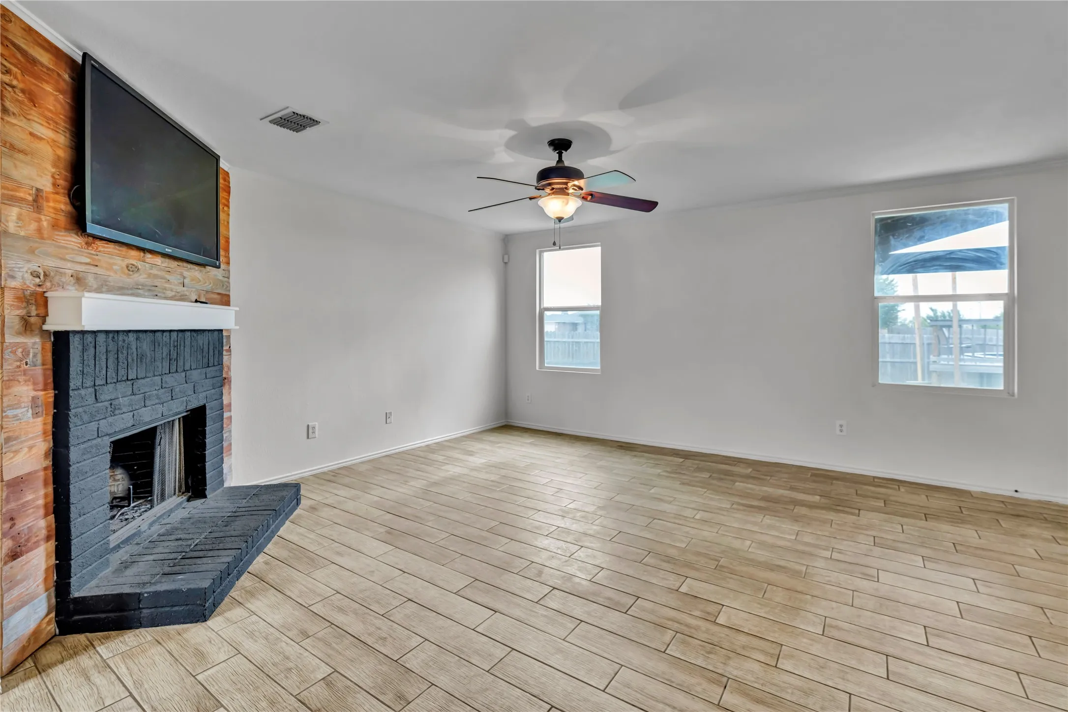 Living space featuring a black brick fireplace with a white mantel and a wood-panel accent wall