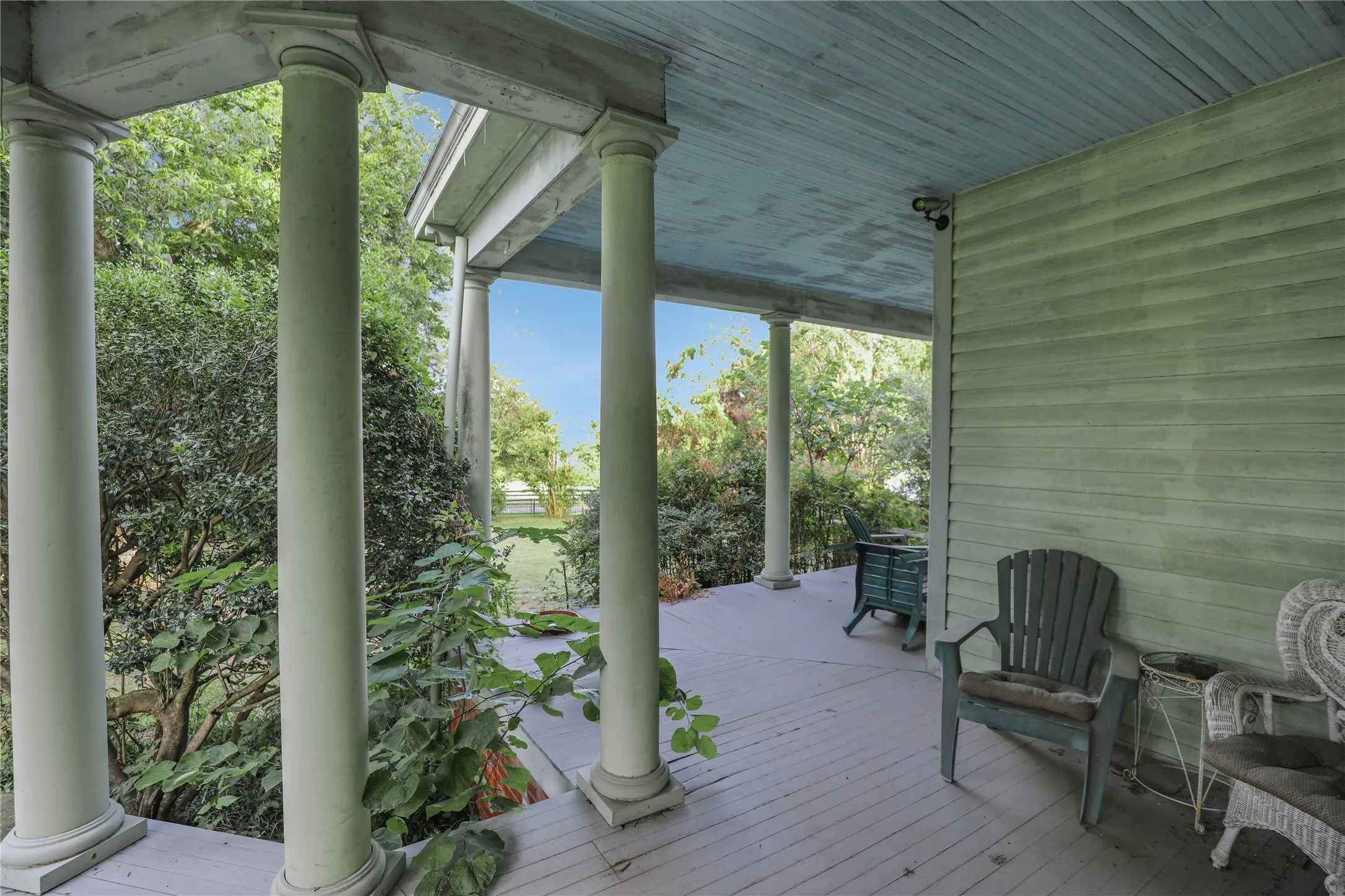 Expansive covered porch featuring substantial round columns, beadboard ceiling, and horizontal siding