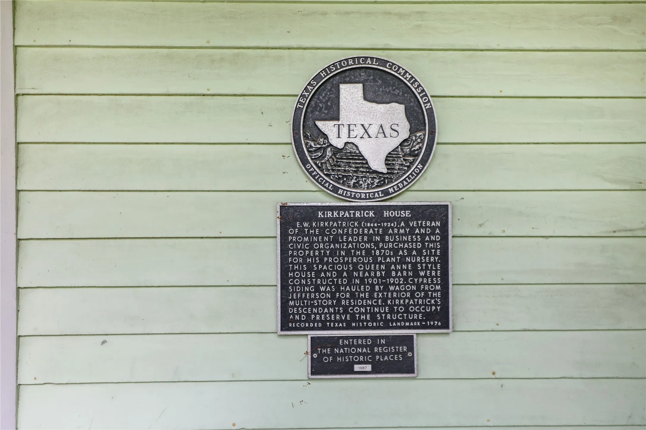 Light green horizontal siding featuring a prominent historical marker