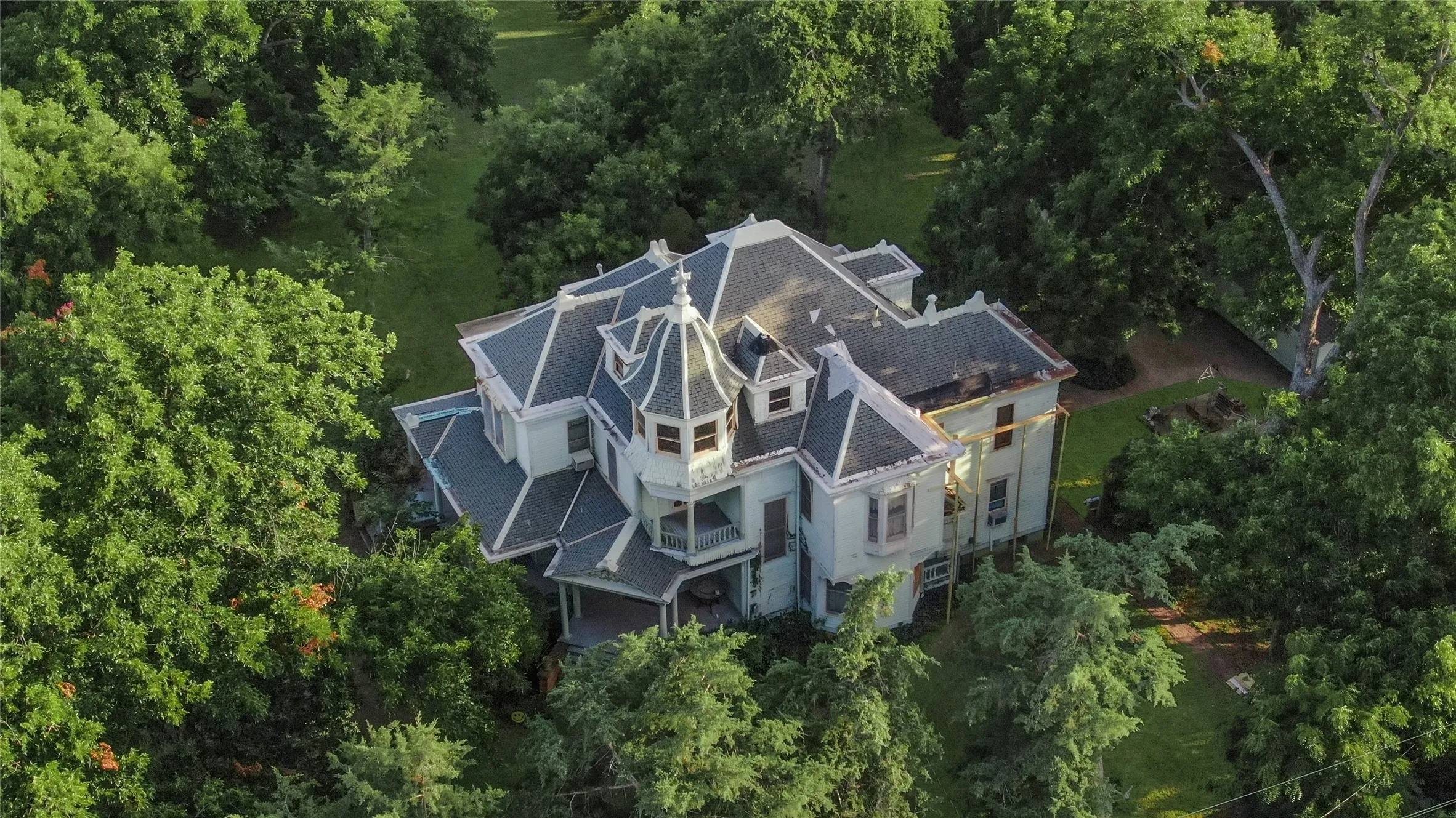 Victorian-style residence with a turret, multiple dormer windows, and a dark shingle roof