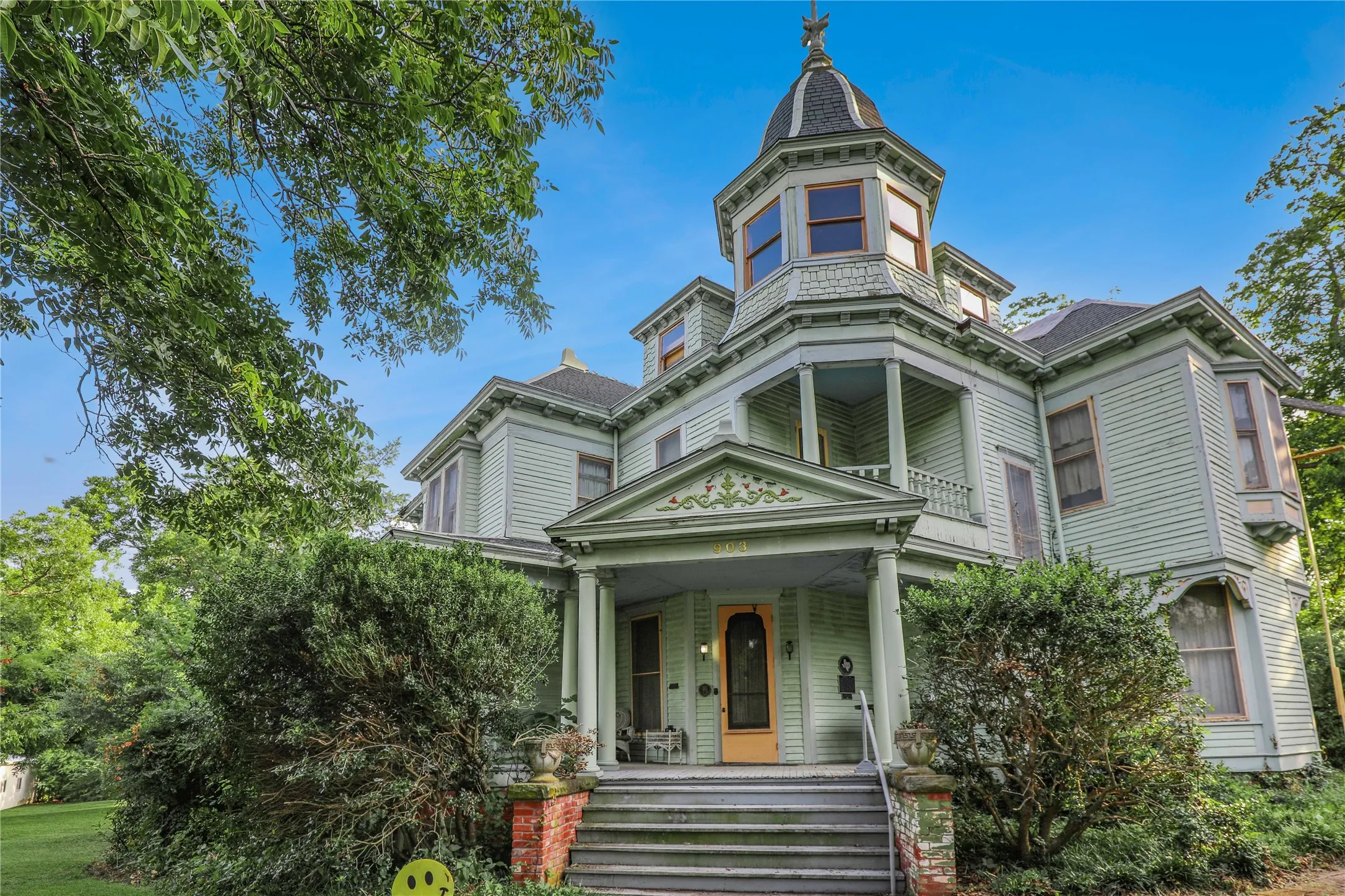 Historic Victorian architecture featuring a conical turret, front porch with decorative balustrade, bay windows, and a prominent entry