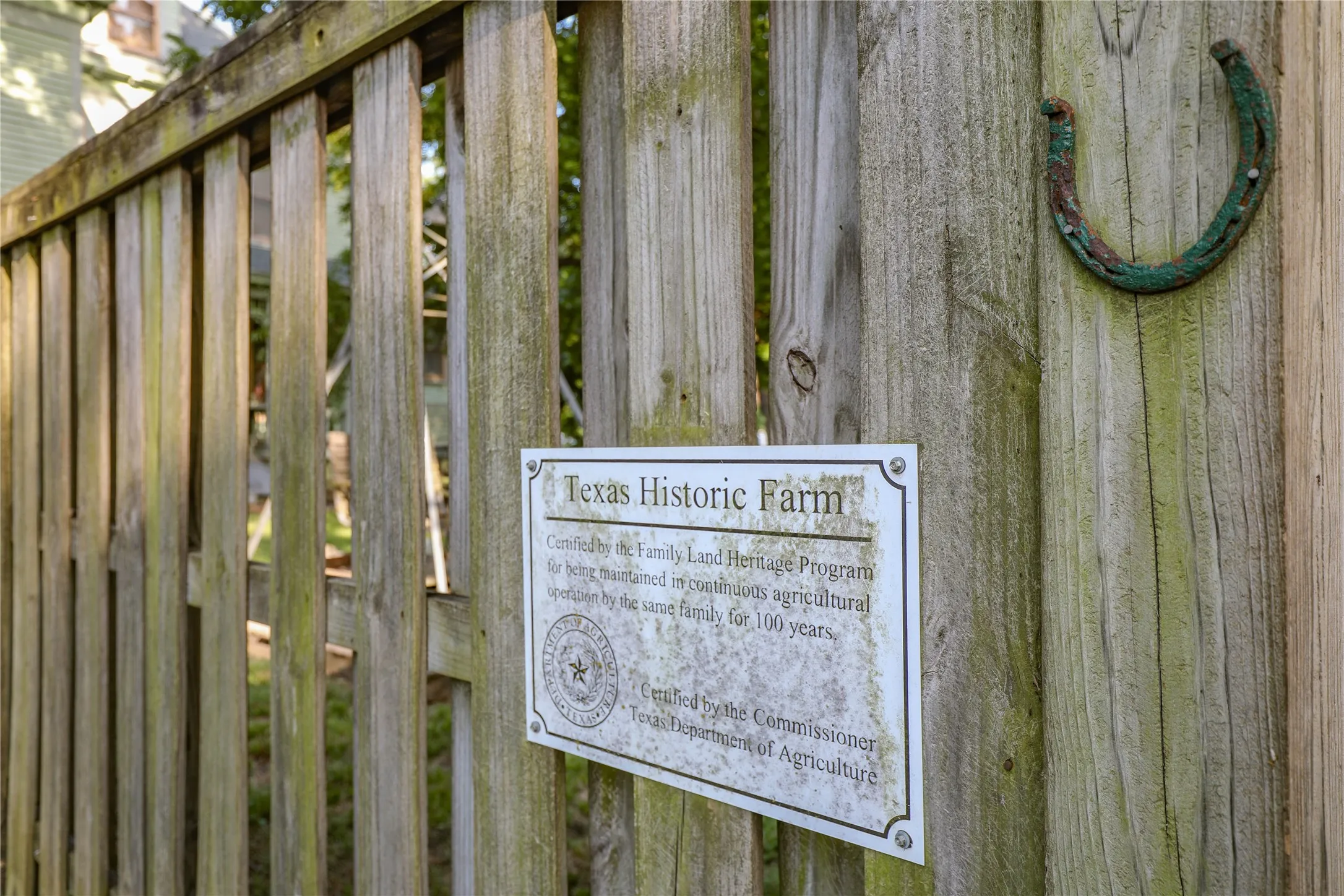 Weathered wooden fence with a Texas Historic Farm plaque and decorative horseshoe