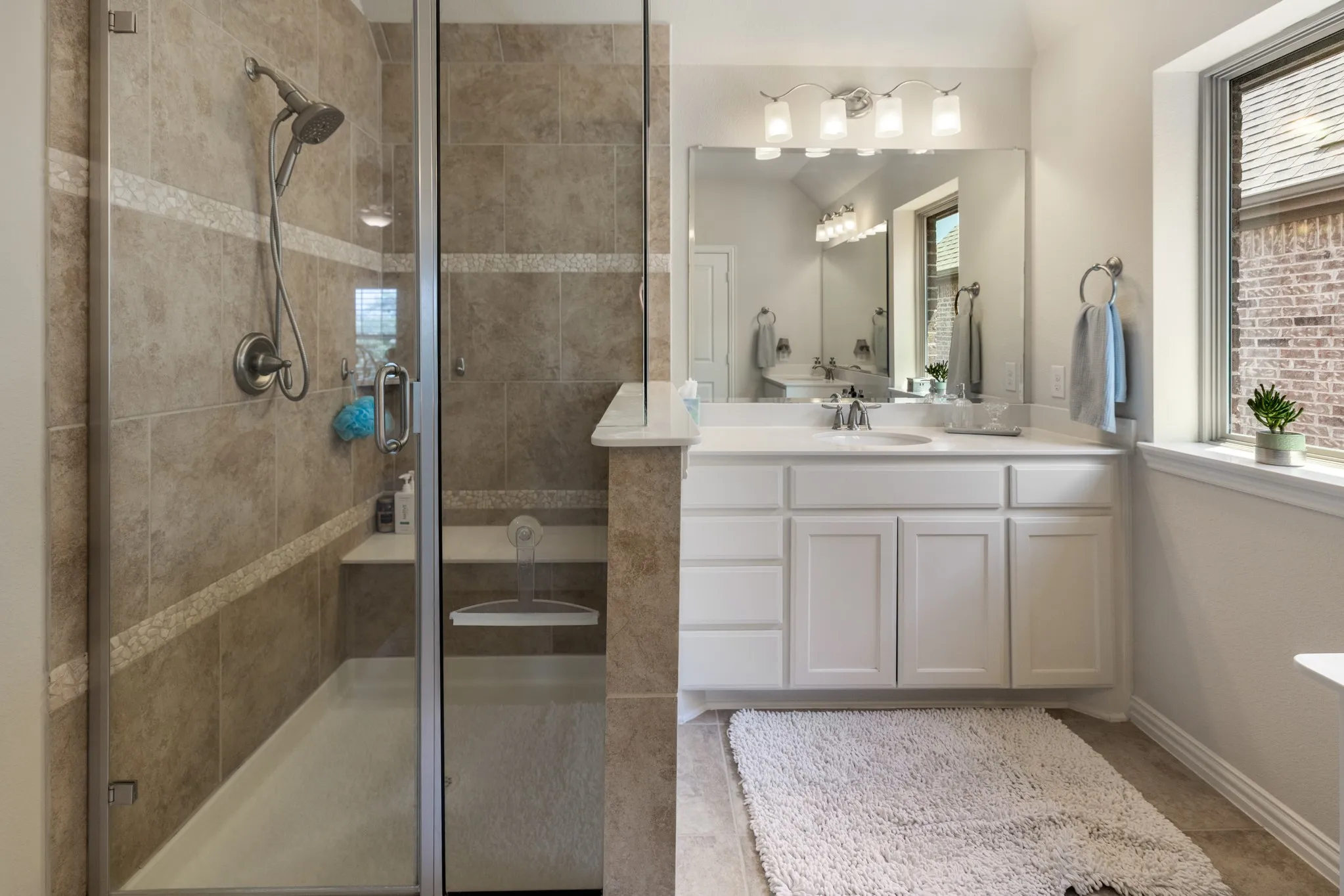 Shower enclosure featuring glass panels, a built-in bench, and a handheld showerhead