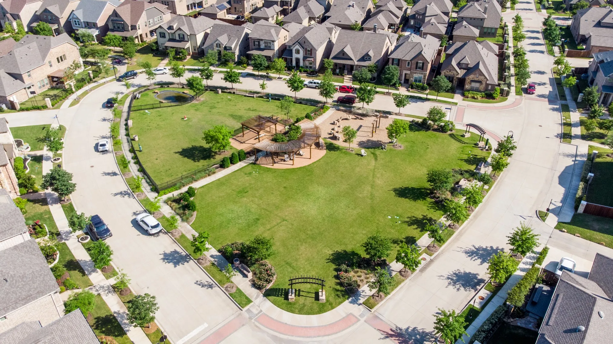 Expansive community green space featuring manicured lawns and mature trees