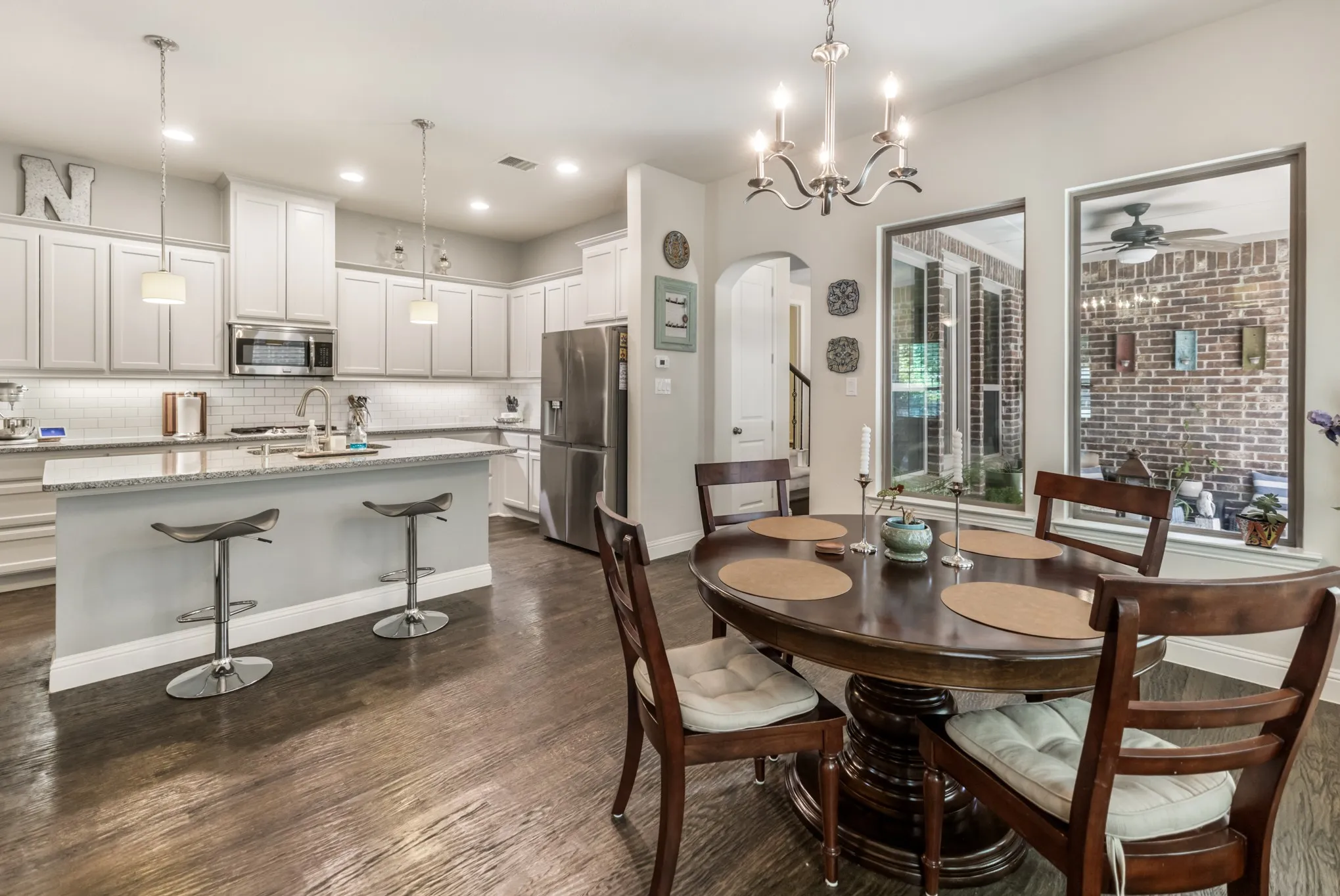 Open-concept kitchen and dining area featuring wood-finish flooring, white cabinetry, a kitchen island with seating, stainless steel appliances, and a dining area with a chandelier