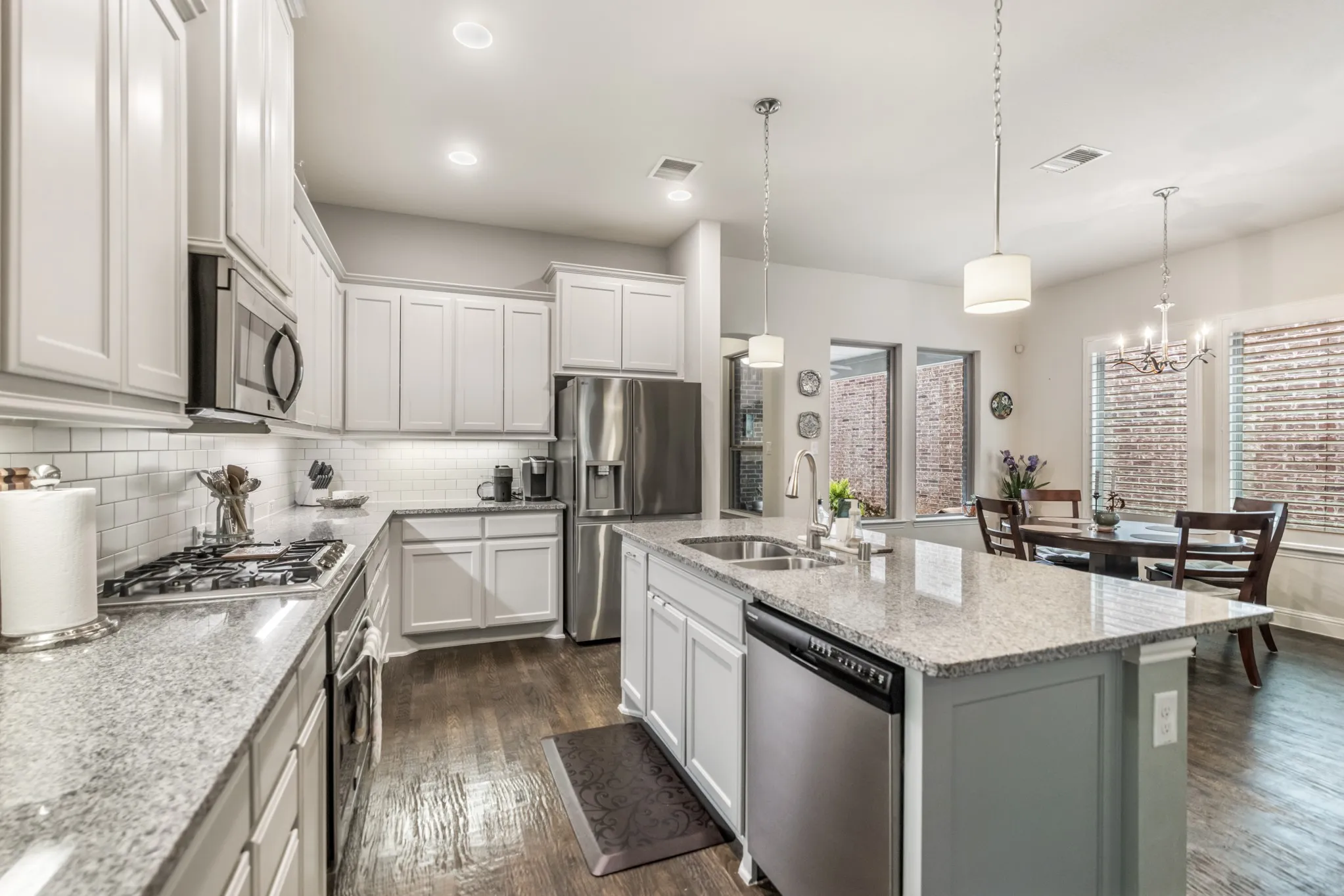 Modern kitchen featuring white shaker cabinetry, stainless steel appliances, granite countertops, a subway tile backsplash, and dark wood-finish flooring