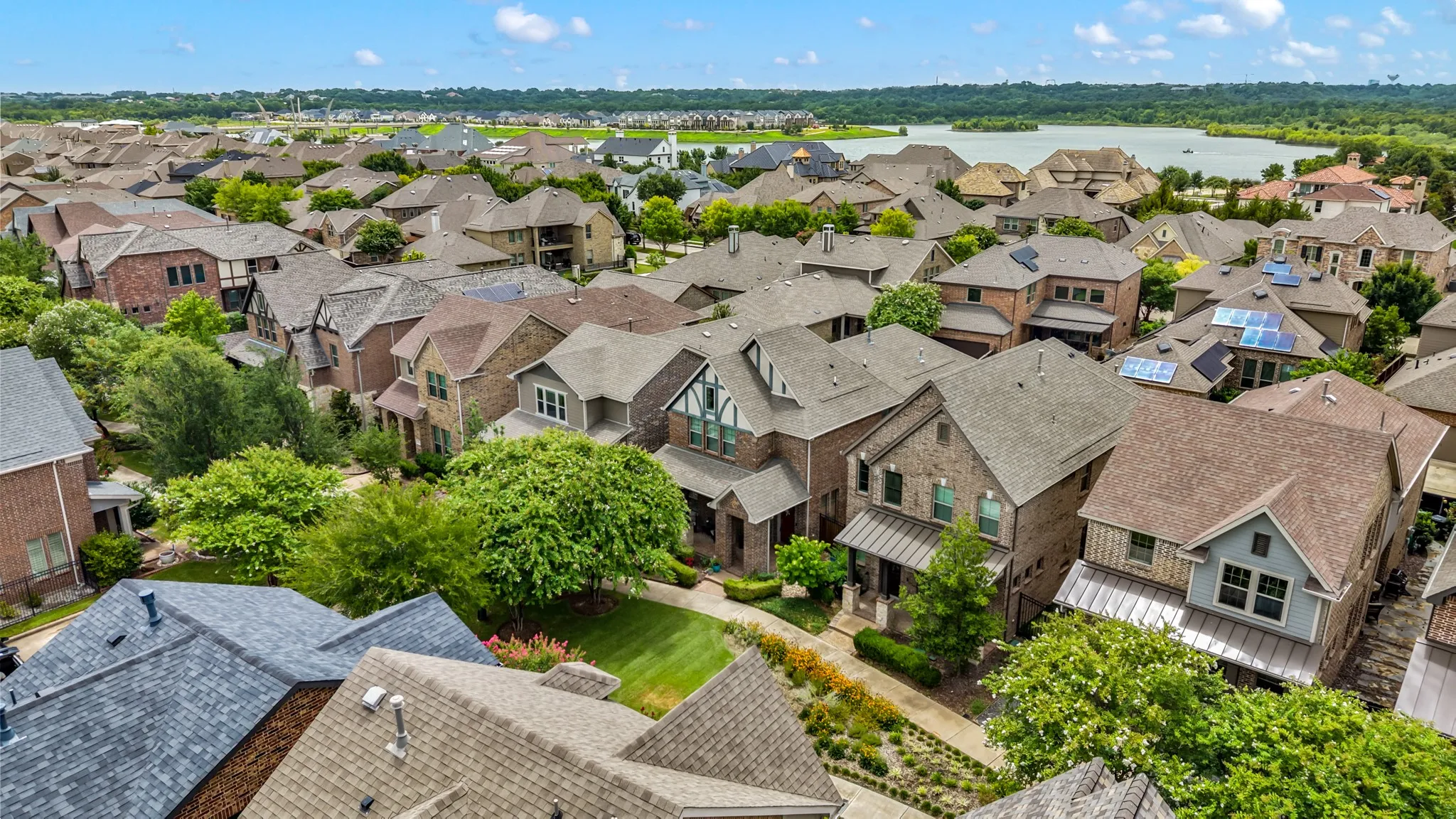 Expansive residential neighborhood featuring a variety of architectural styles, mature landscaping, and an apparent lake in the distance