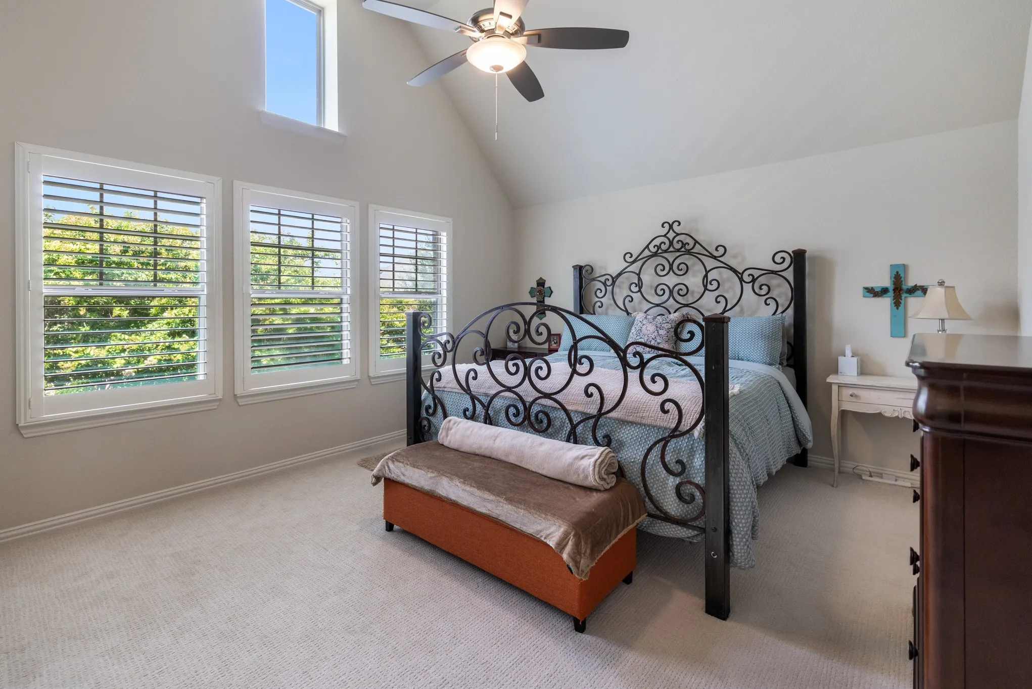Vaulted ceiling bedroom with light-toned wall paint and plush carpeting