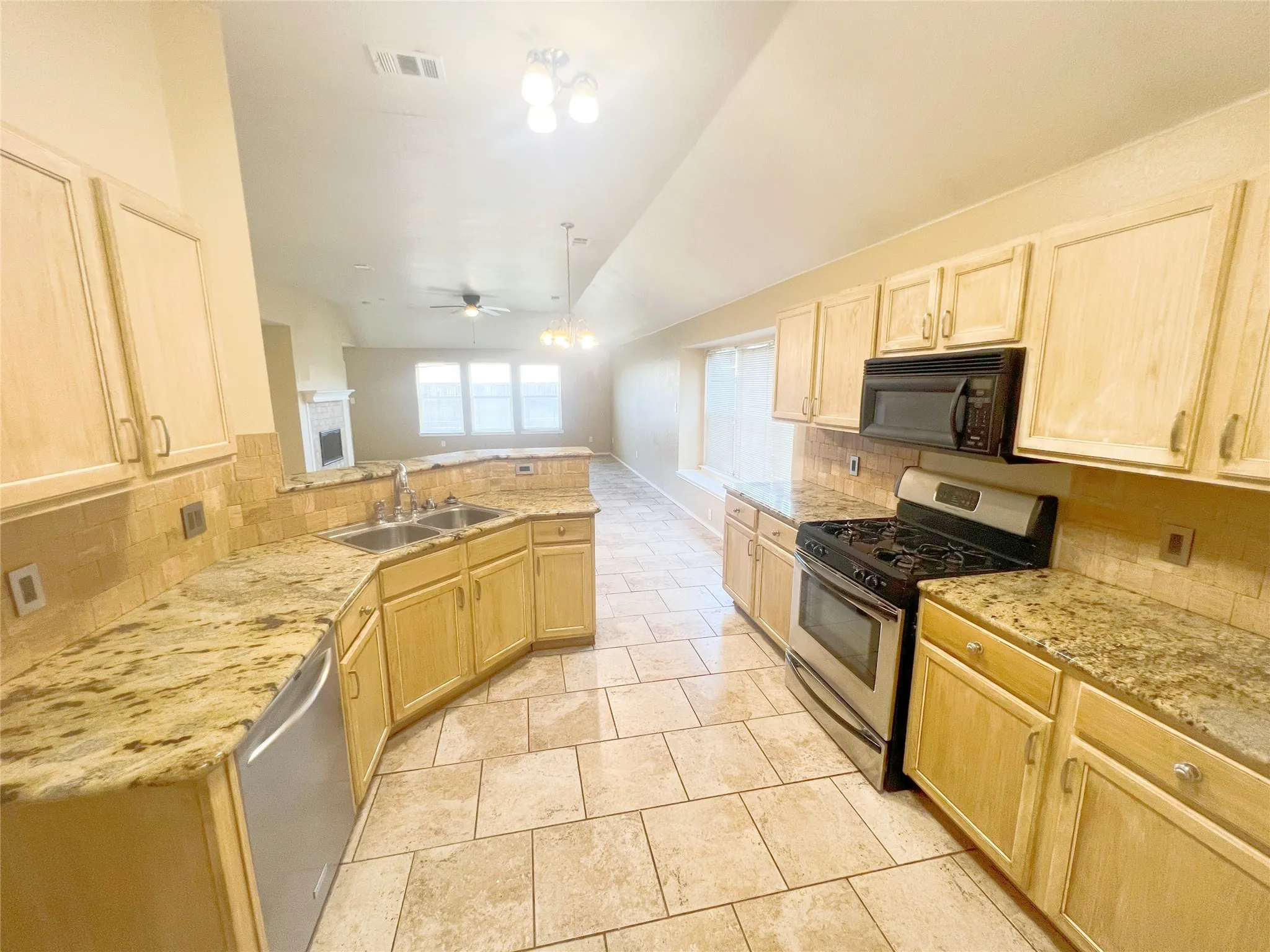 Kitchen featuring light wood-finish cabinetry, granite-style countertops, stainless steel appliances, and tile flooring