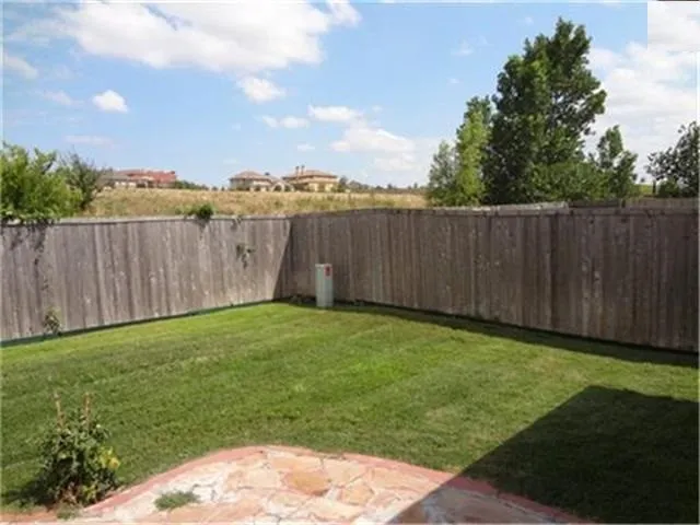 Expansive fenced backyard featuring a grassy lawn and a flagstone patio area