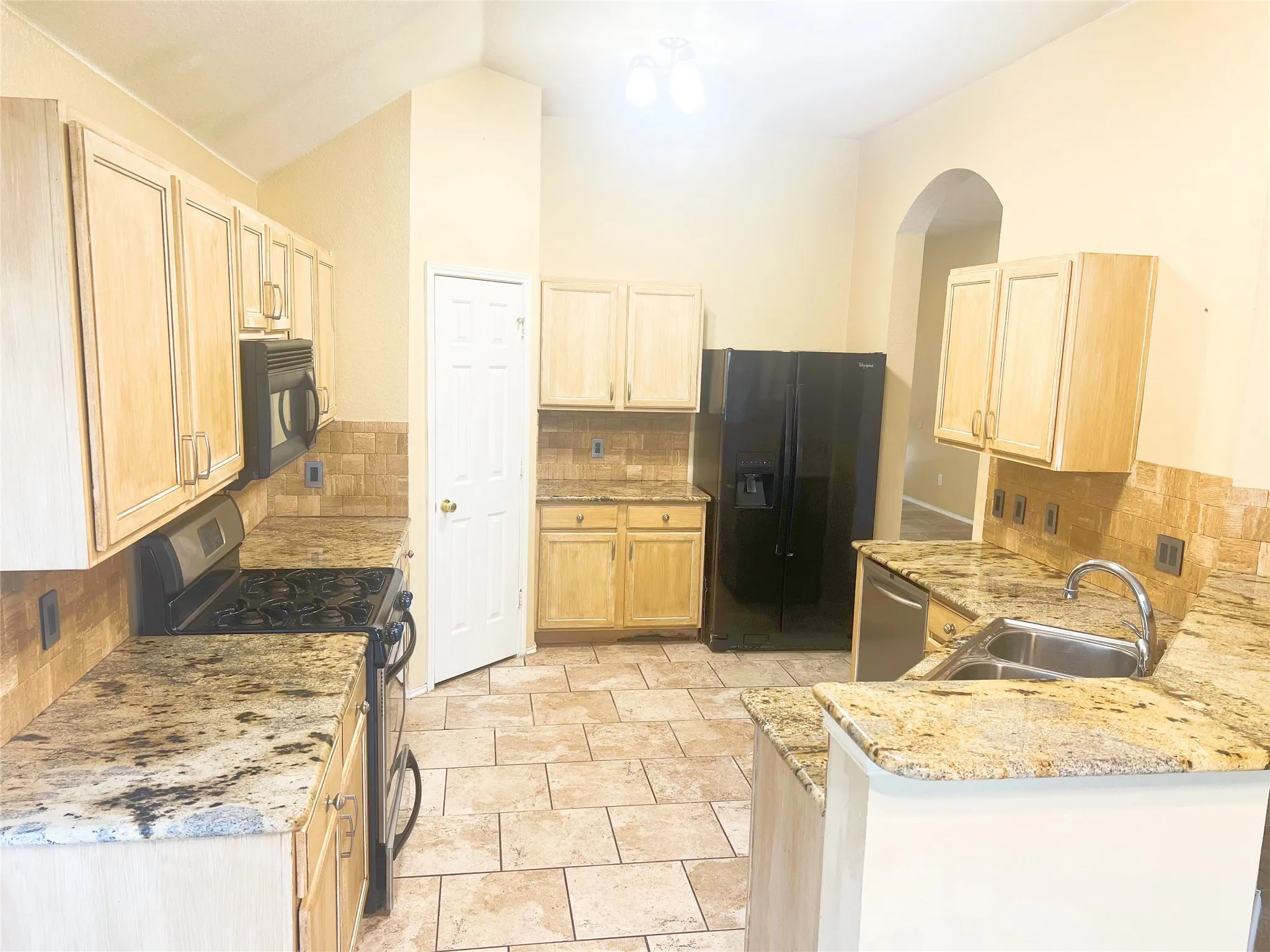 Kitchen featuring granite countertops, light wood cabinetry, tiled flooring, a gas range, and a built-in microwave