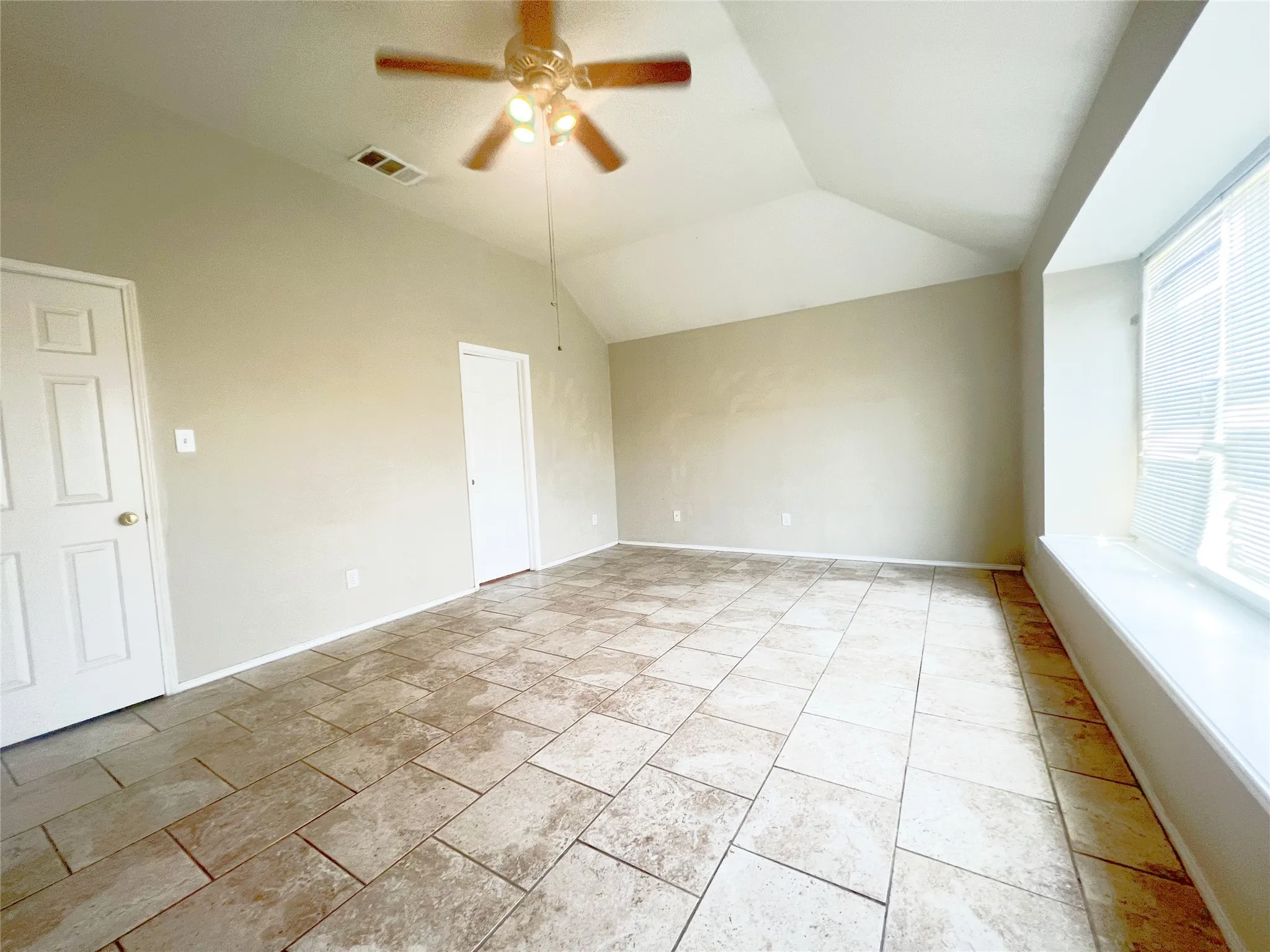 Spacious room featuring vaulted ceilings, a ceiling fan, and large tile flooring throughout
