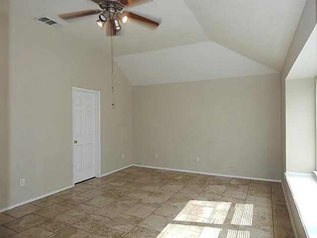 Room featuring vaulted ceilings, ceiling fan with integrated lighting, tile flooring, and a window with a deep sill