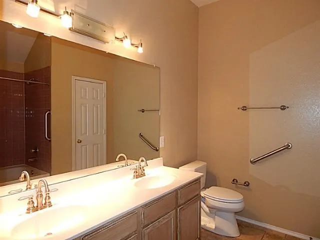 Bathroom featuring a dual vanity with integrated sinks, brushed bronze faucets, and a light-toned wood-finish cabinet