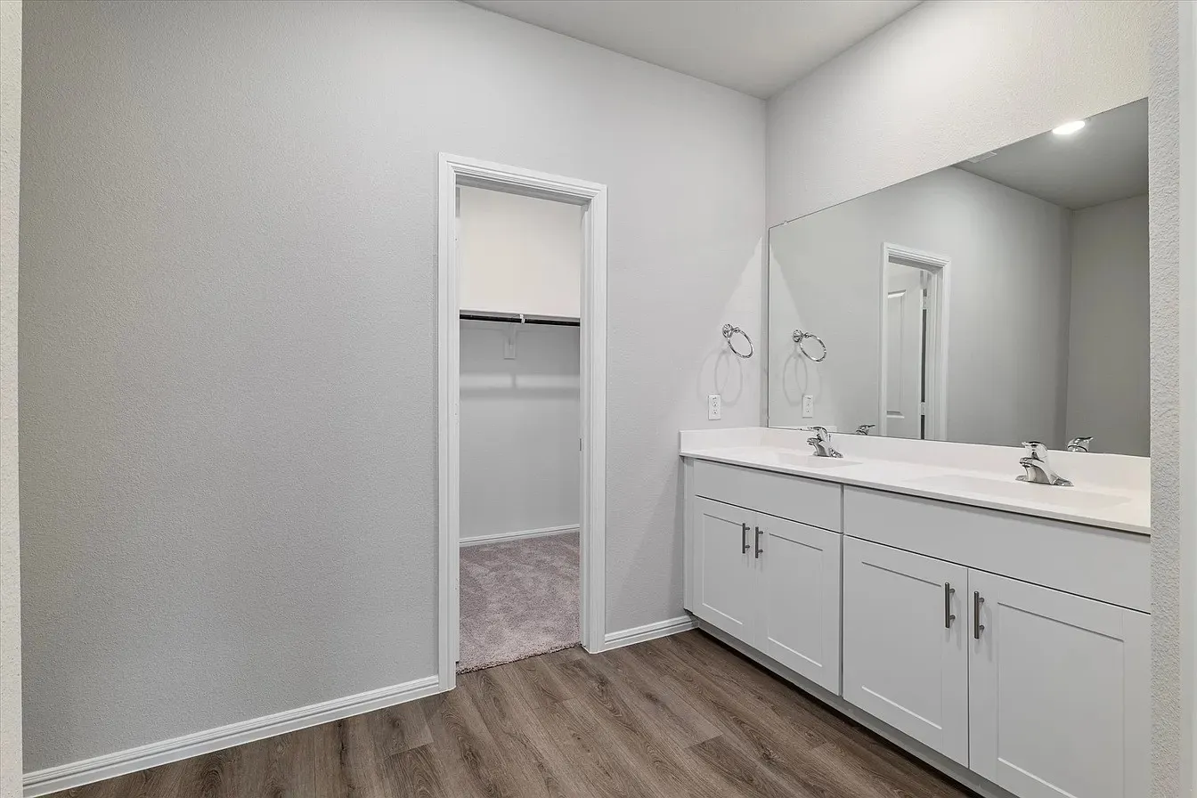 Double vanity featuring white cabinetry, integrated sinks, and a full-width mirror