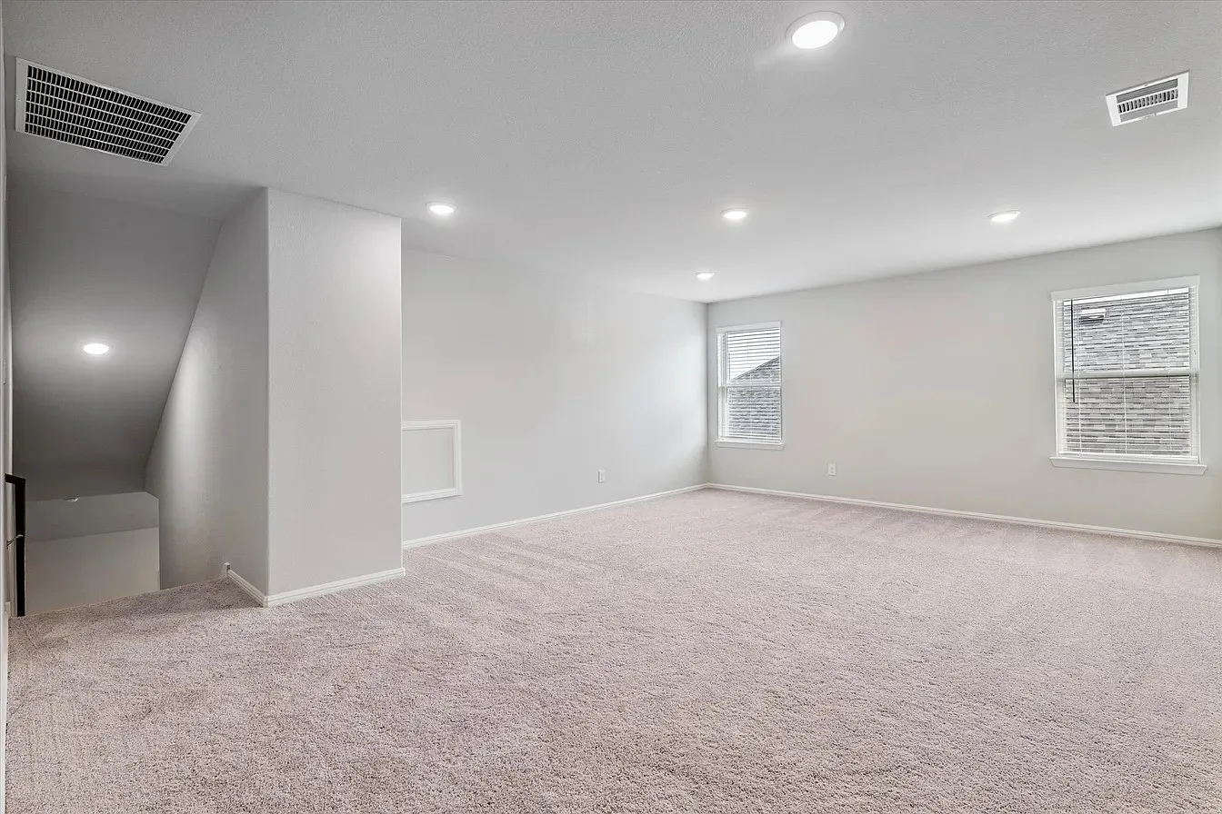 Spacious carpeted room with recessed lighting and neutral wall tones