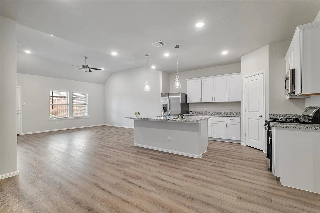 Open-concept living space featuring wood-finish flooring, recessed lighting, and a vaulted ceiling