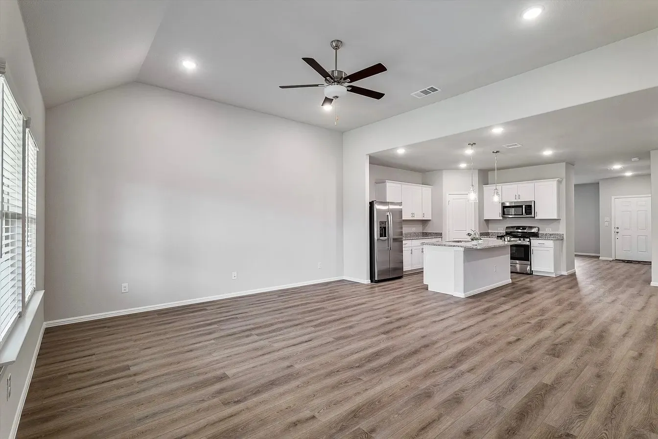 Open-concept living space featuring wood-finish flooring, a vaulted ceiling, and recessed lighting