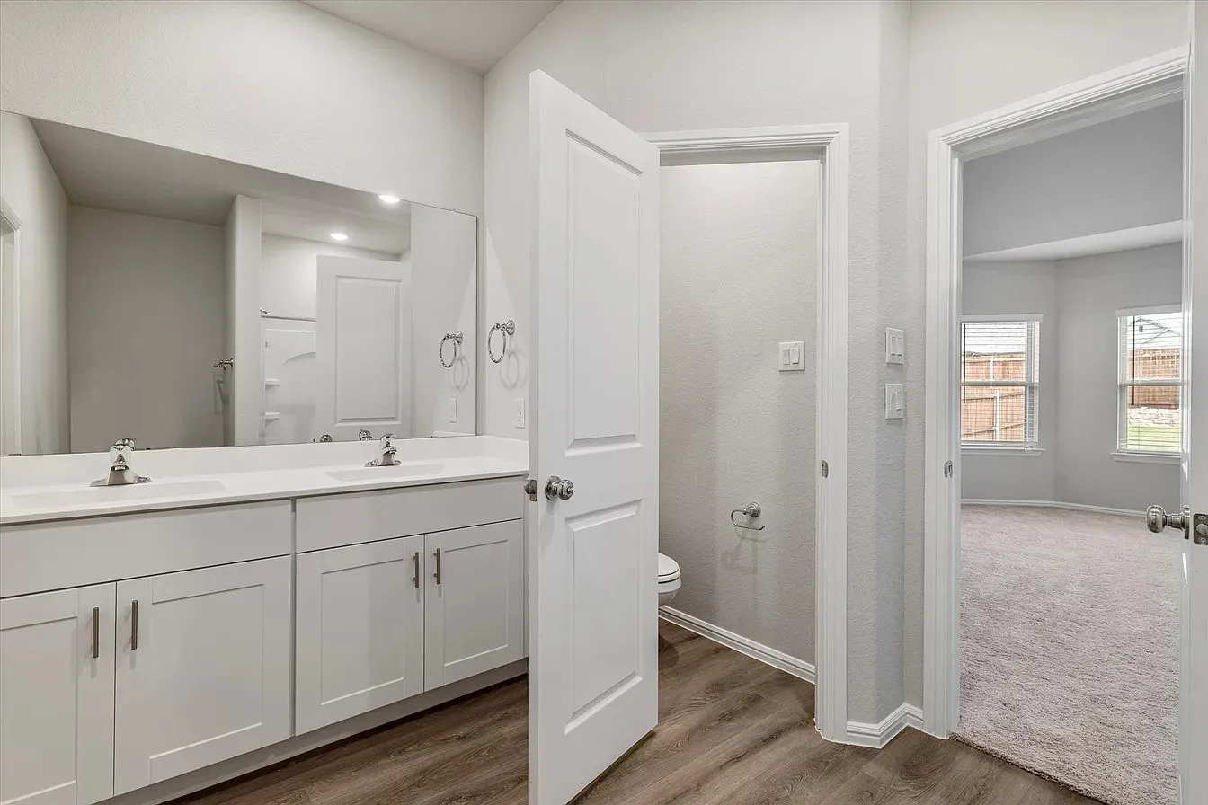 Bathroom featuring a dual vanity with white cabinetry, integrated sinks, and a full-width mirror