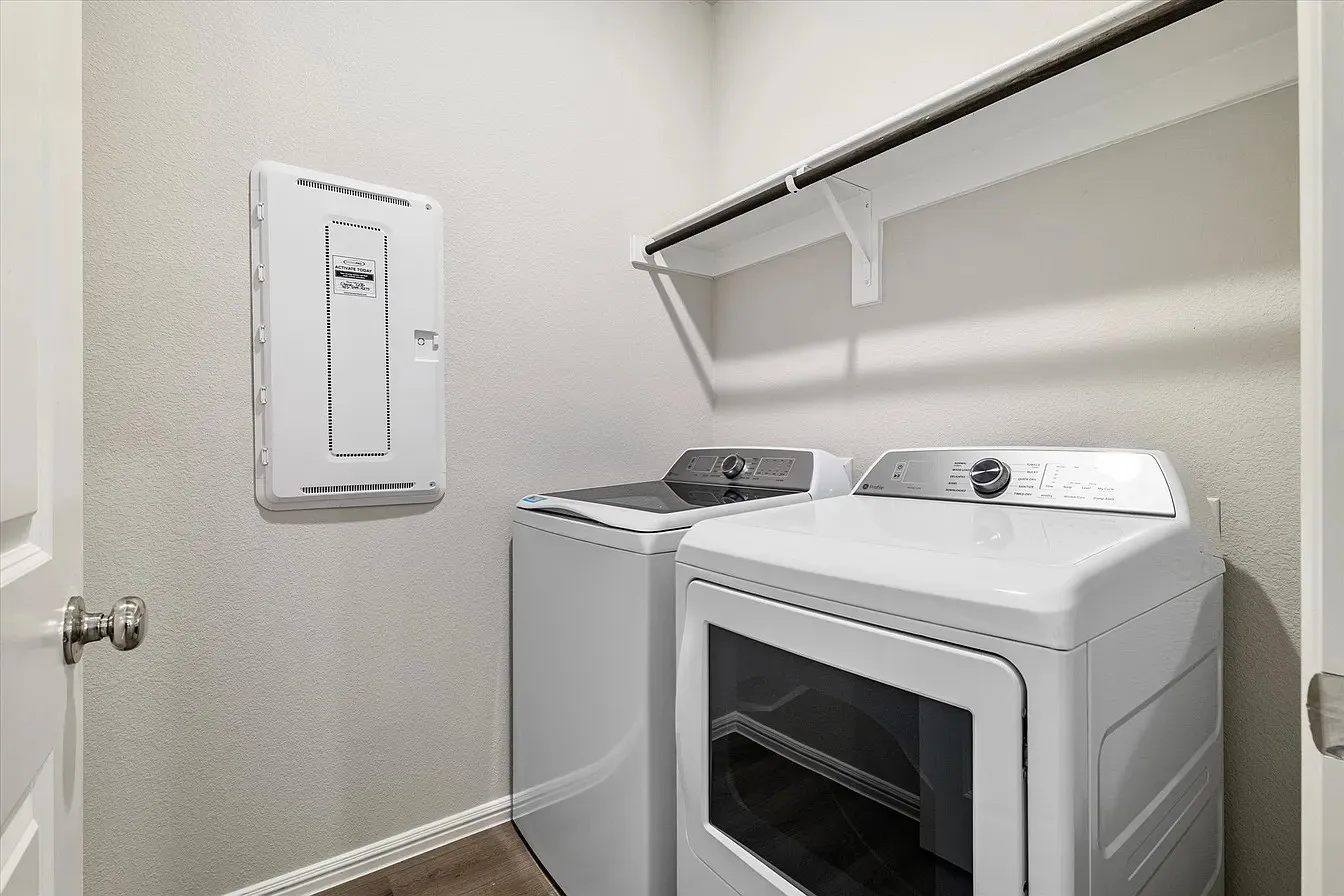 Dedicated laundry area featuring wood-finish flooring, white baseboards, and light-toned walls