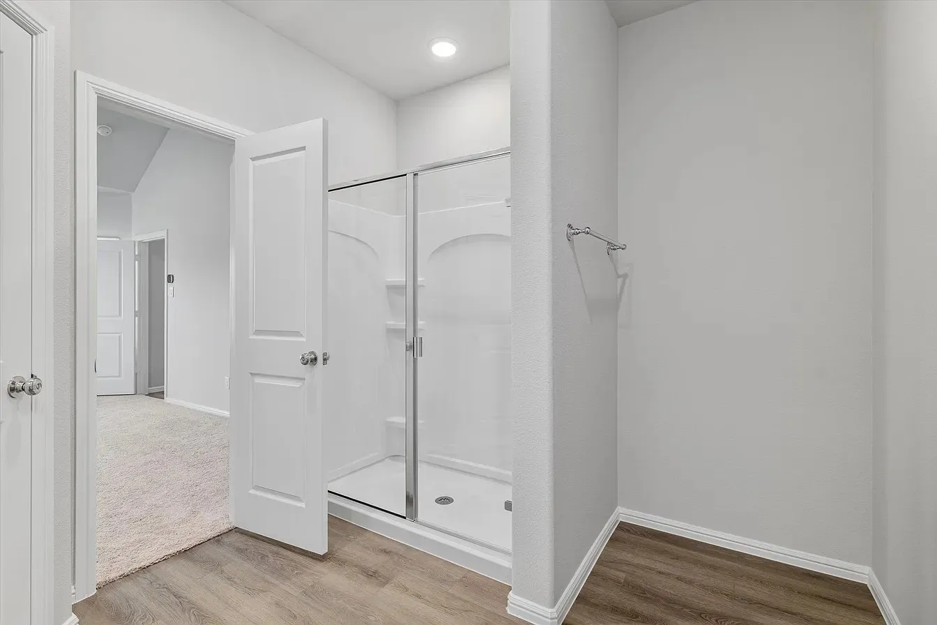 Shower enclosure with clear glass door, integrated shelving, and white base