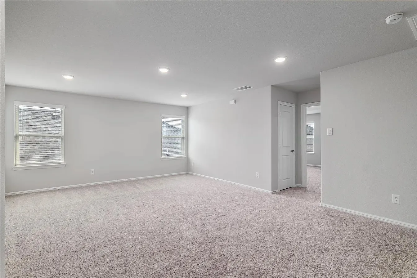 Spacious room featuring neutral carpeting, light-toned walls, and recessed lighting