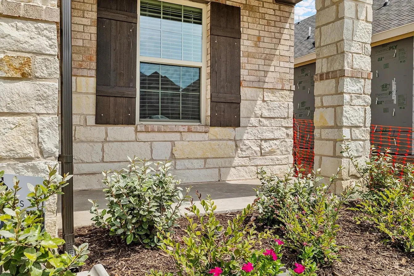 Stone and brick exterior featuring a prominent window with dark shutters