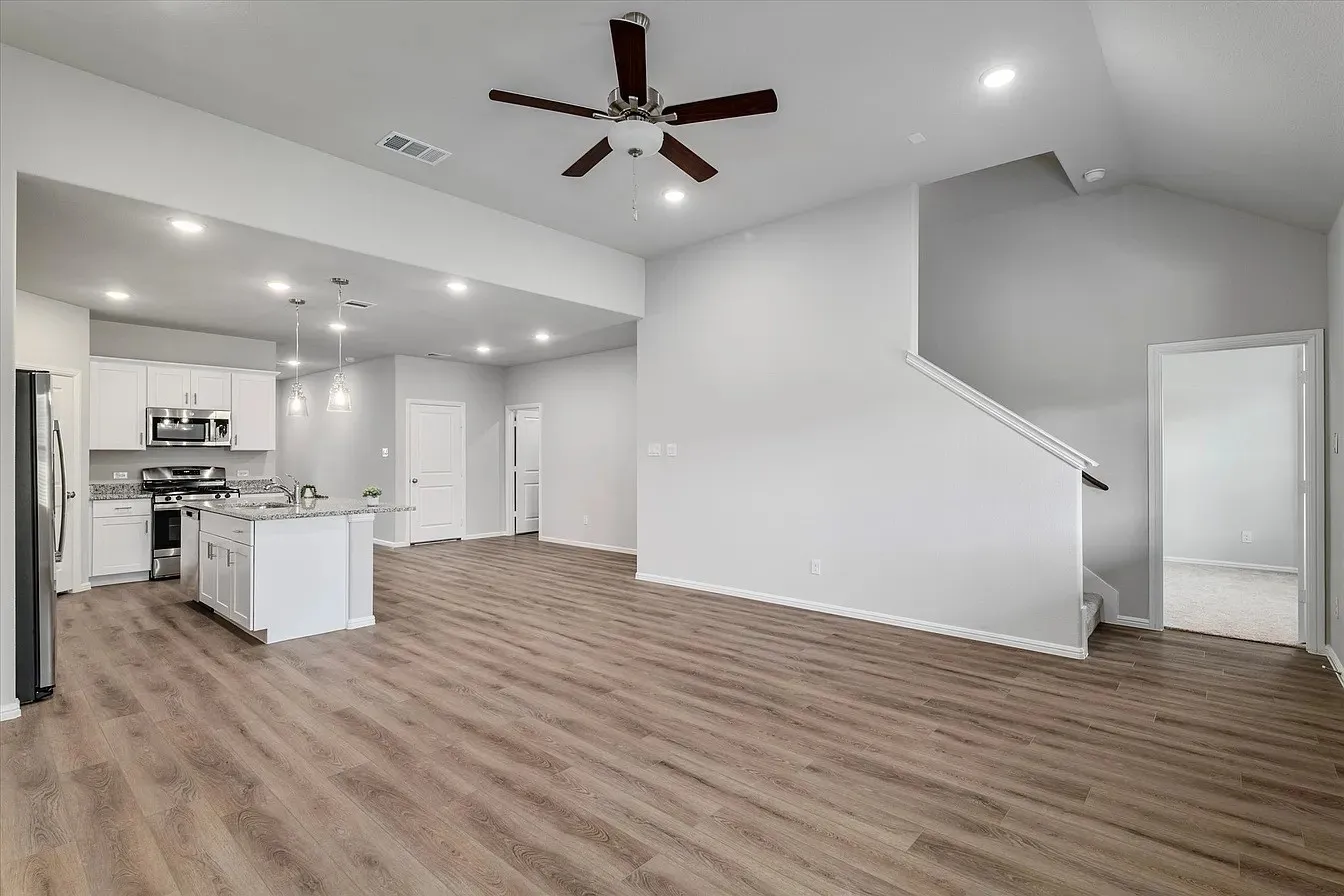 Spacious open-concept interior featuring wood-finish flooring, recessed lighting, and a contemporary ceiling fan