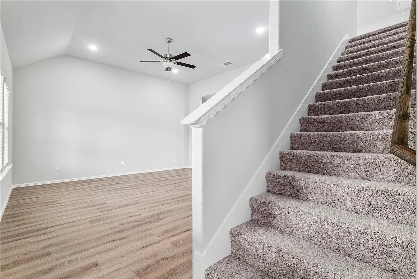 Carpeted staircase with a wood railing and white newel post