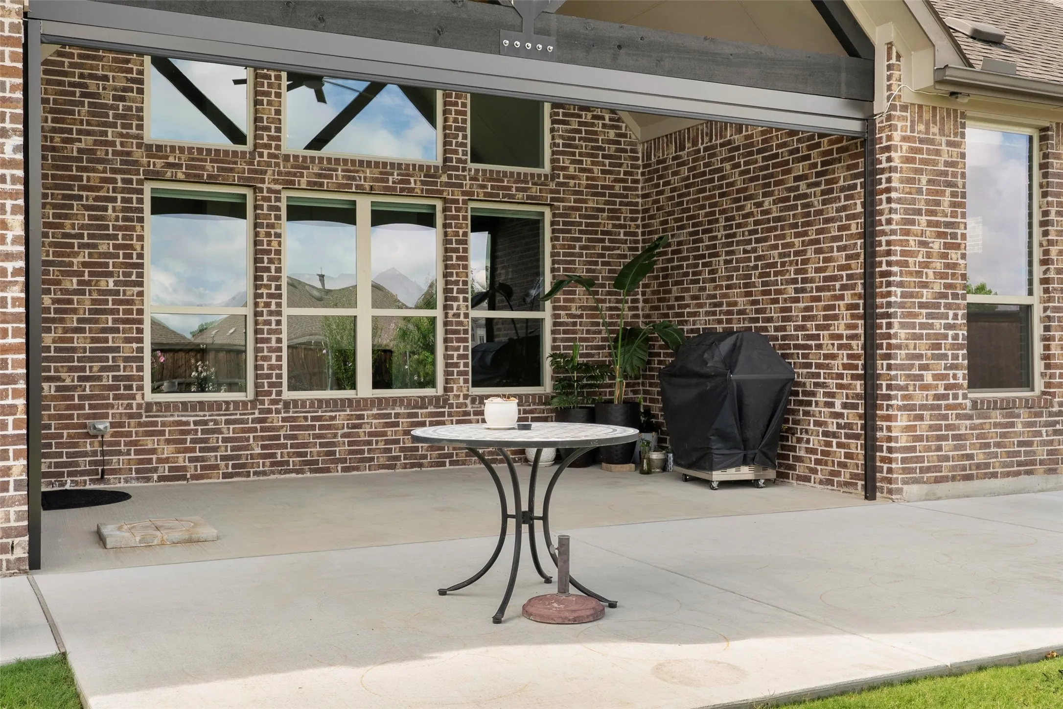 Expansive covered patio featuring a concrete surface, brick exterior, and multiple large windows