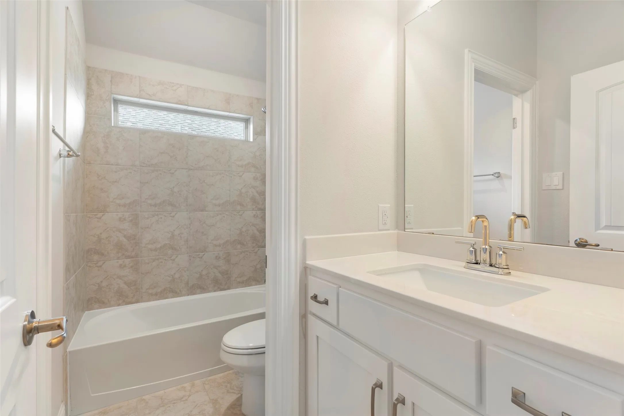 Bathroom featuring a white vanity with a rectangular undermount sink, a polished chrome and gold-tone faucet, and a large mirror