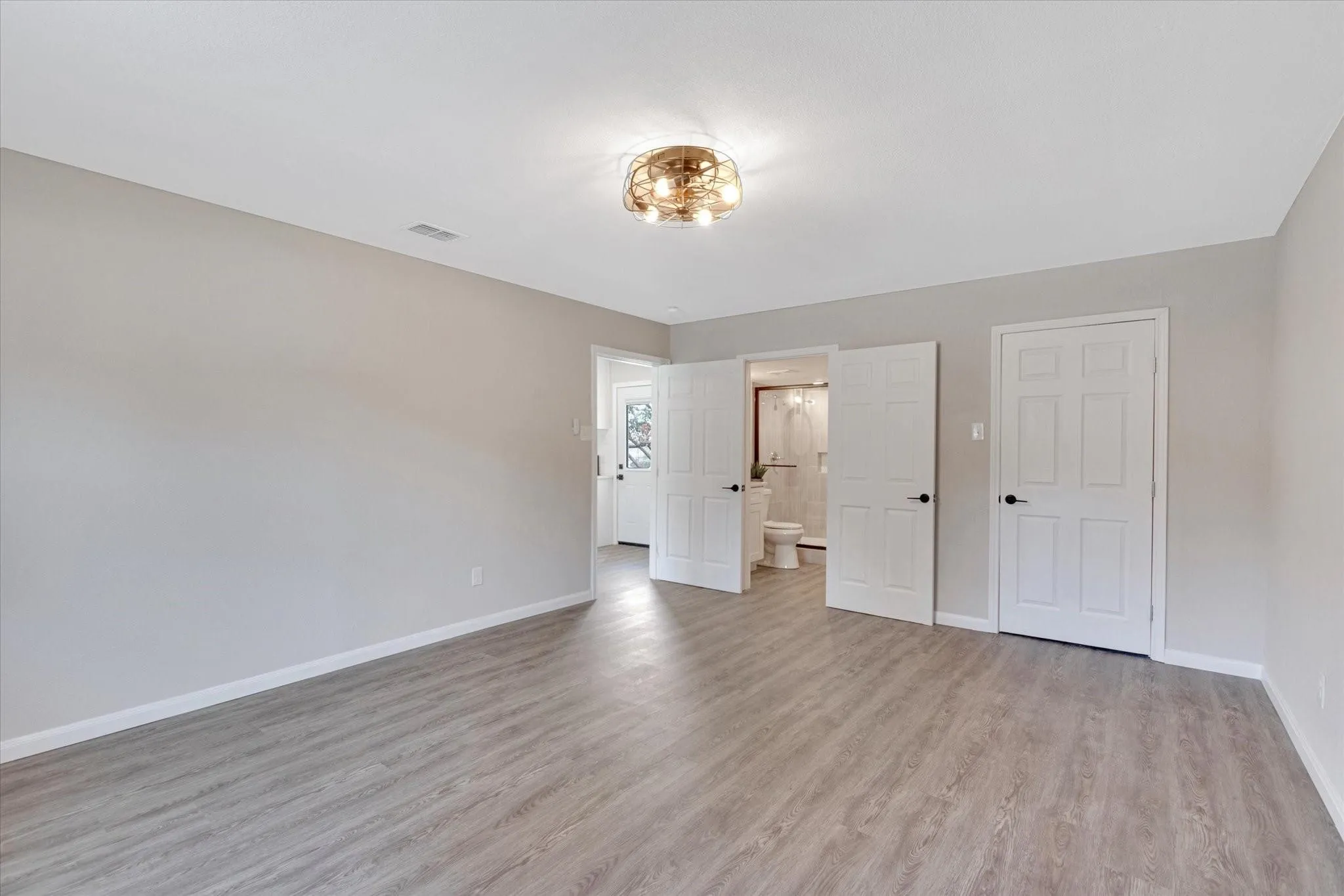 Primary Bedroom looking to kitchen, walk in closet and bath/laundry room.
