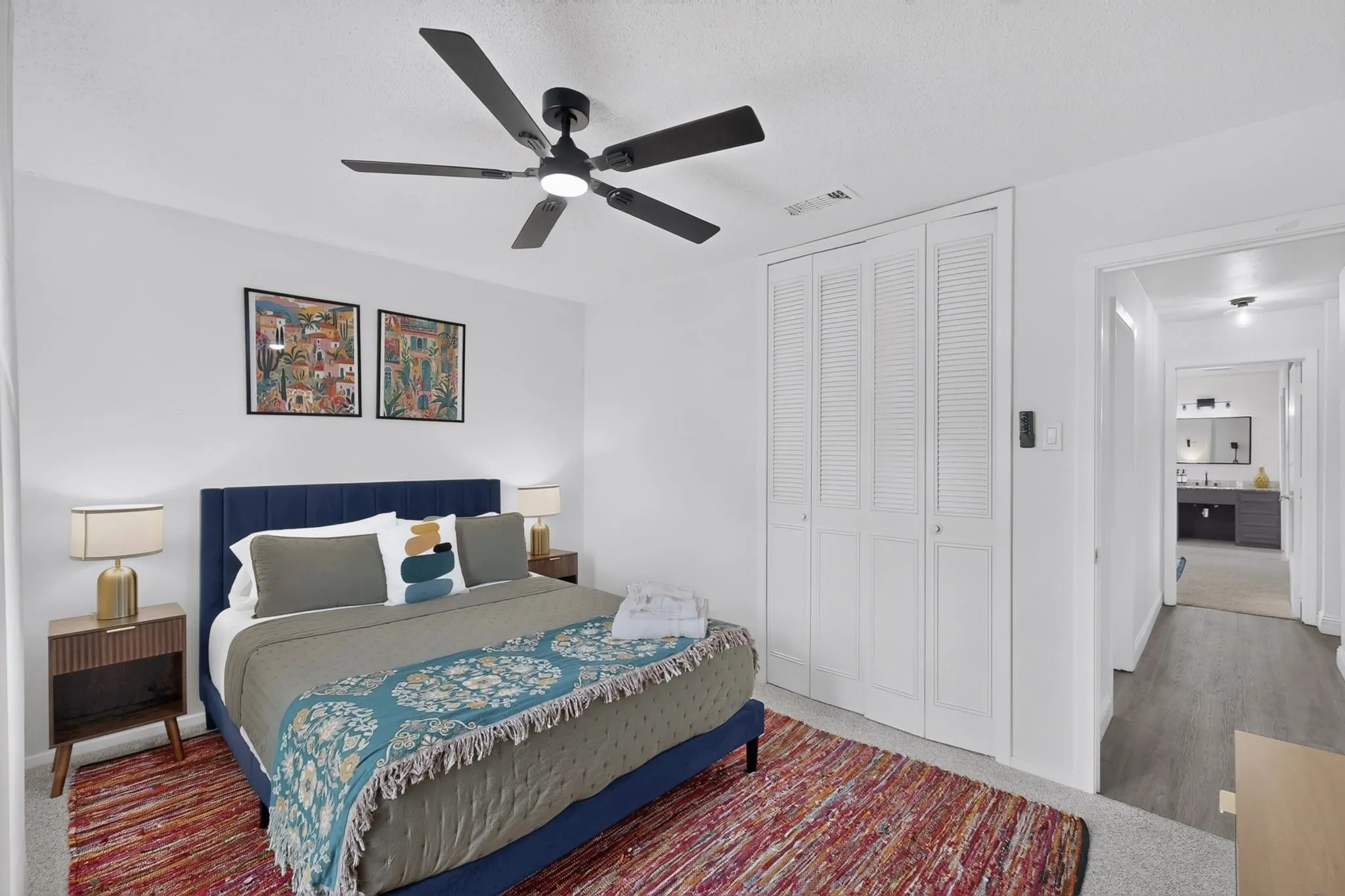 Bedroom with white walls, a black ceiling fan, and bi-fold louvered closet doors