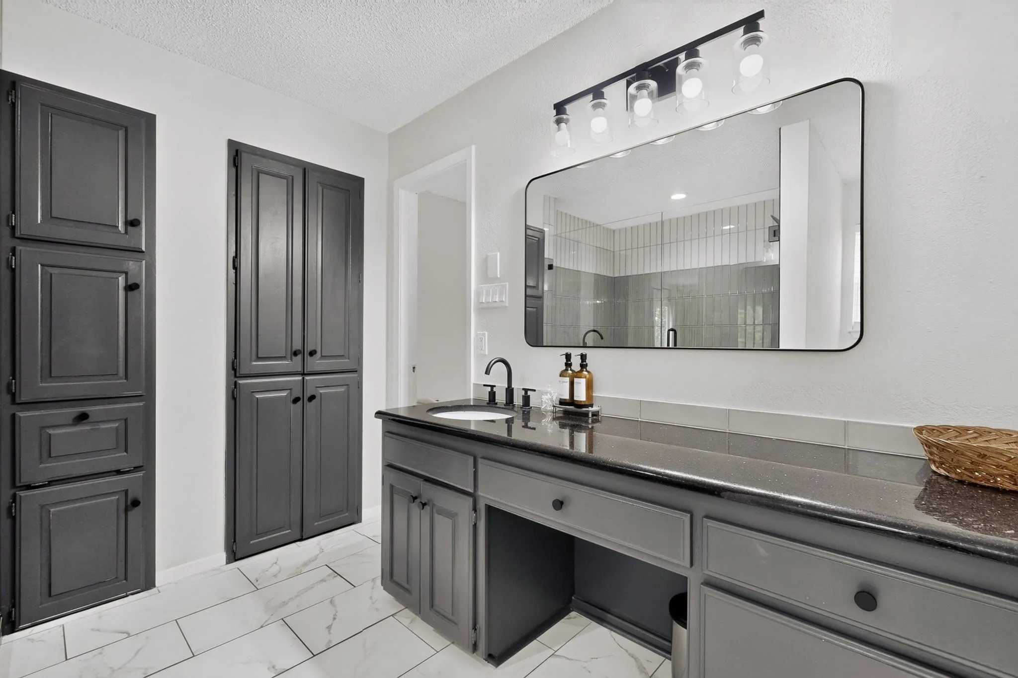 Bathroom featuring dark gray cabinetry, a black countertop, and a single undermount sink with a matte black faucet