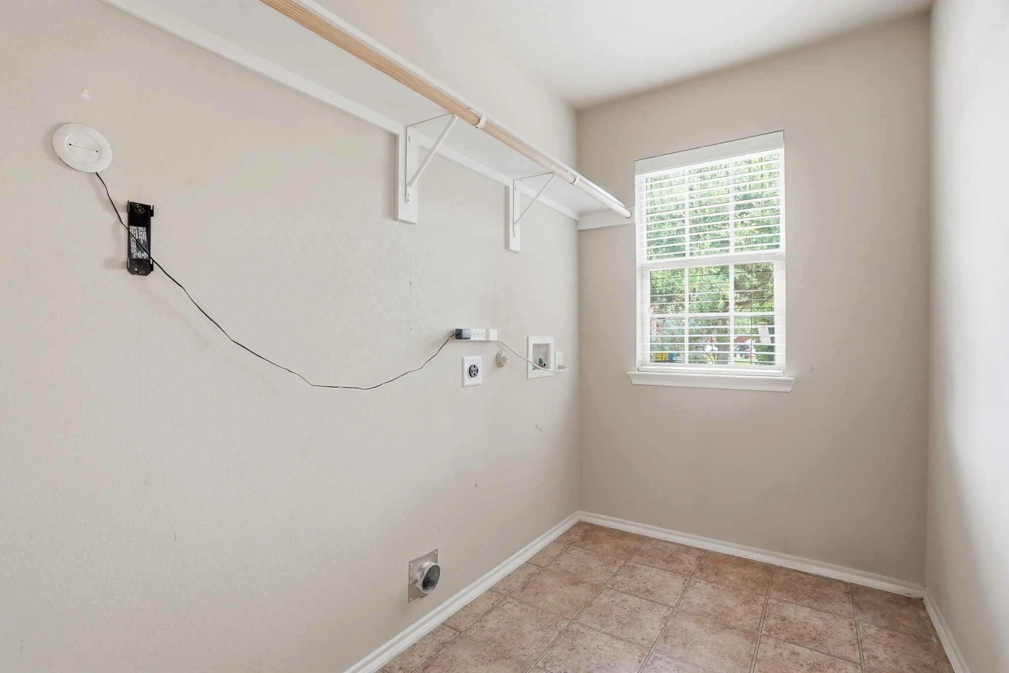 Dedicated utility space featuring tile flooring and a window with blinds