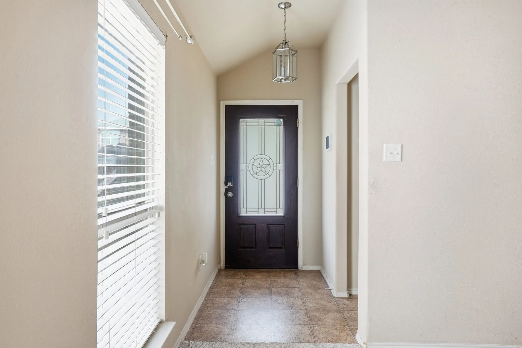Entryway featuring a dark wood door with decorative glass, a hanging lantern-style light fixture, and tile flooring