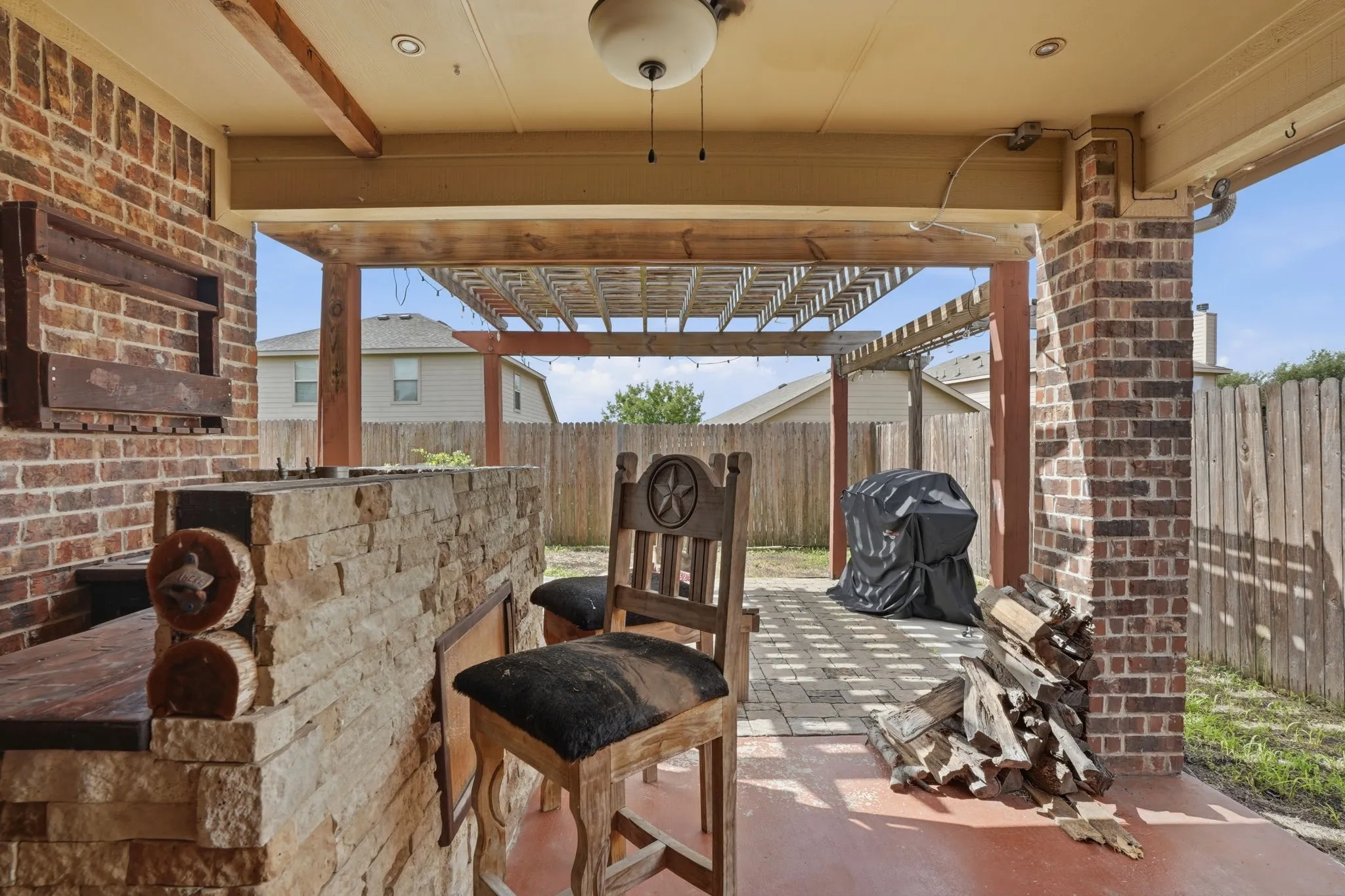 Covered patio area featuring a stone and brick outdoor kitchen with built-in countertop