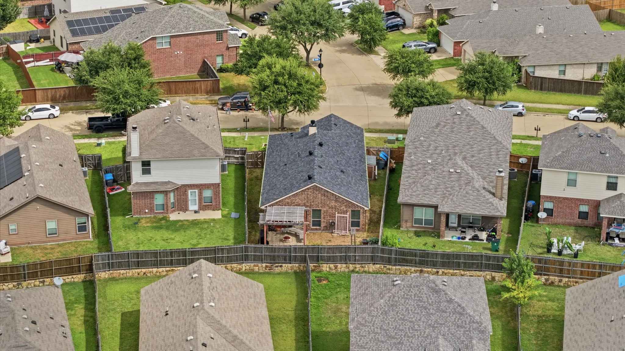 Residential property featuring a shingled roof, brick and siding exterior, and a fenced backyard