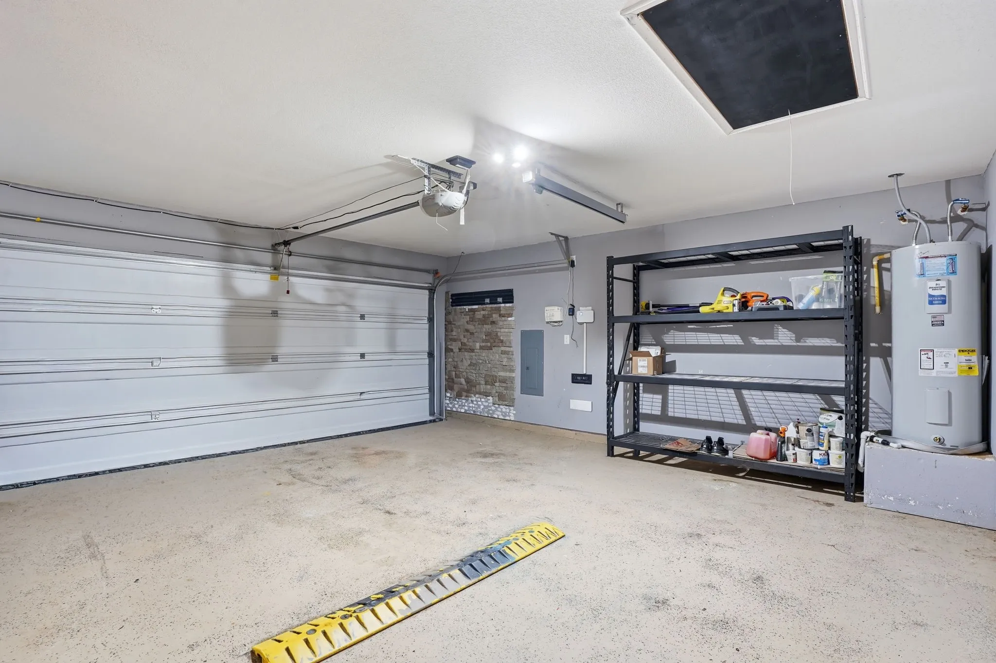 Garage featuring an automatic overhead door, concrete flooring, and ample storage shelving