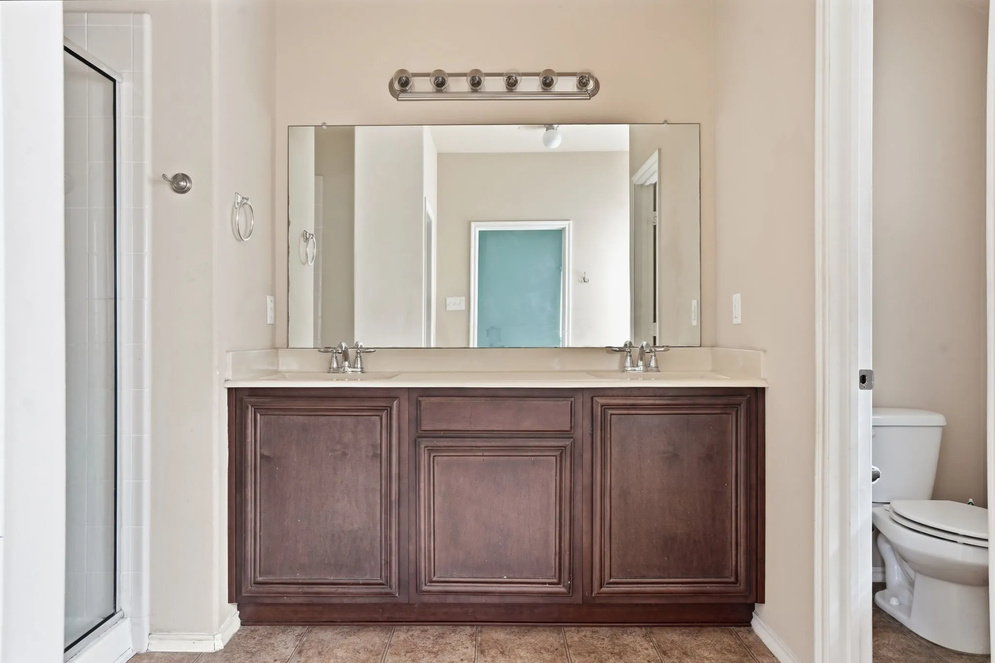 Double vanity featuring a light-colored countertop, dual sinks with chrome faucets, and dark wood cabinetry