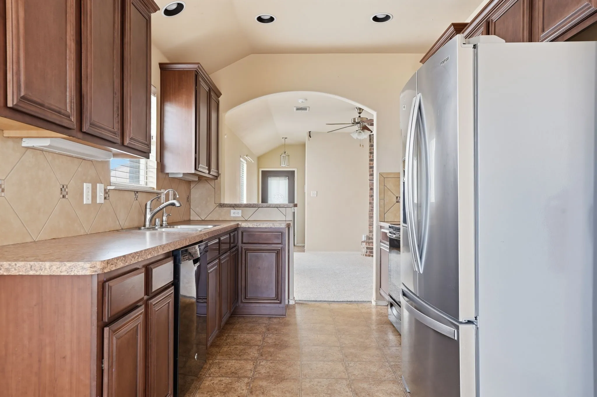 Kitchen with ample wood cabinetry, patterned tile backsplash, and a stainless steel sink
