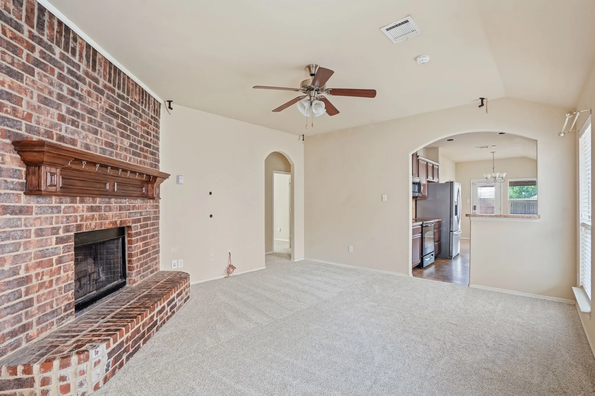 Spacious room with a brick fireplace and wood mantel