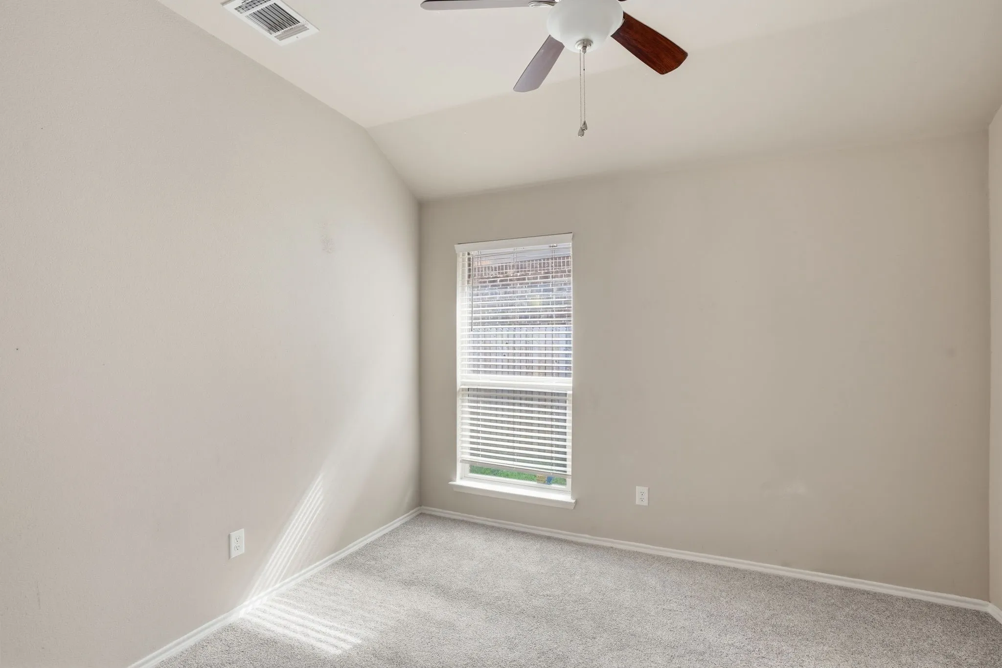 Room featuring neutral wall tones, textured carpeting, and a sloped ceiling