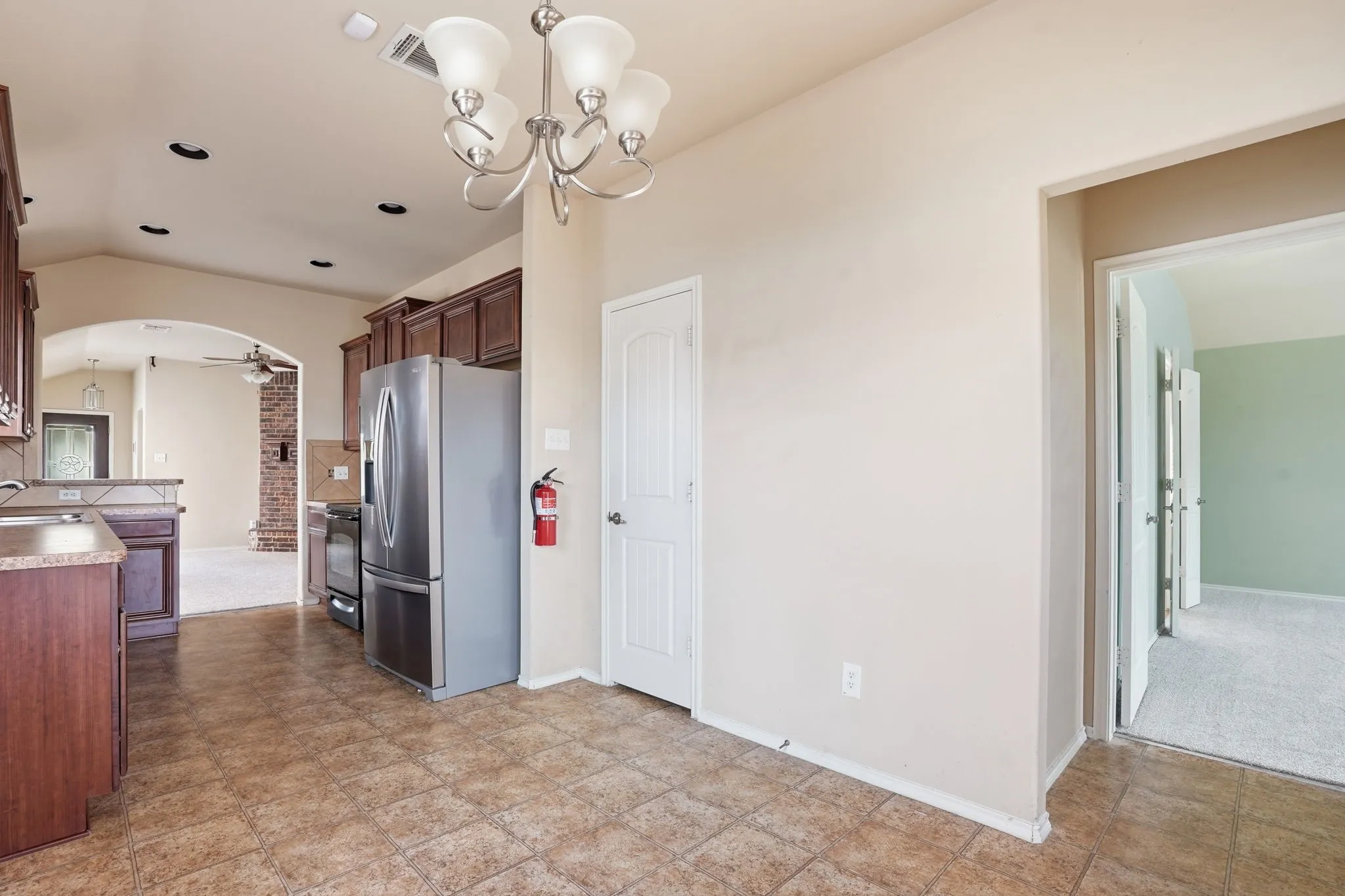 Open-concept kitchen with tile flooring, wood cabinetry, and stainless steel appliances