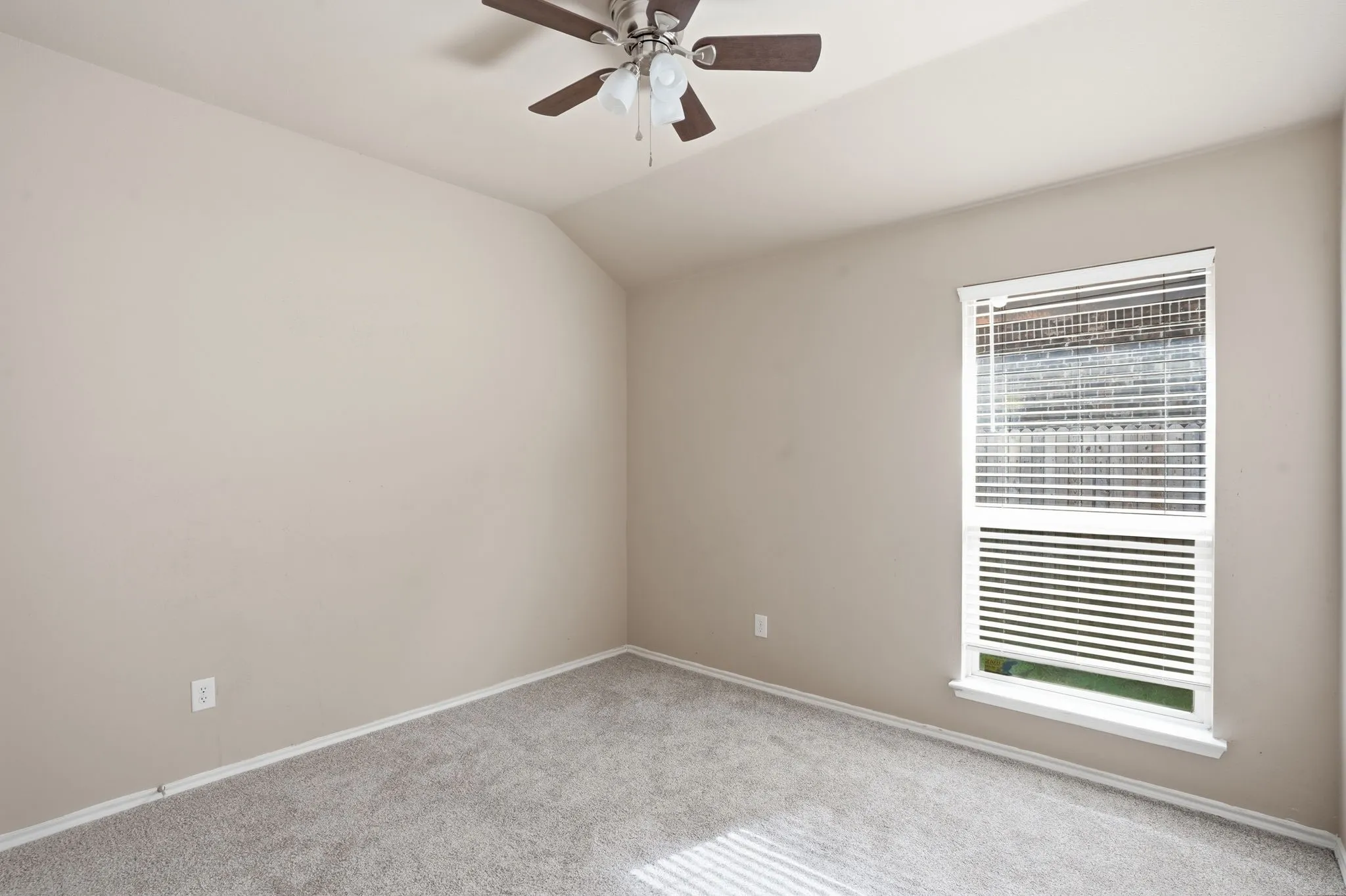 Neutral-toned bedroom with textured carpeting and a sloped ceiling