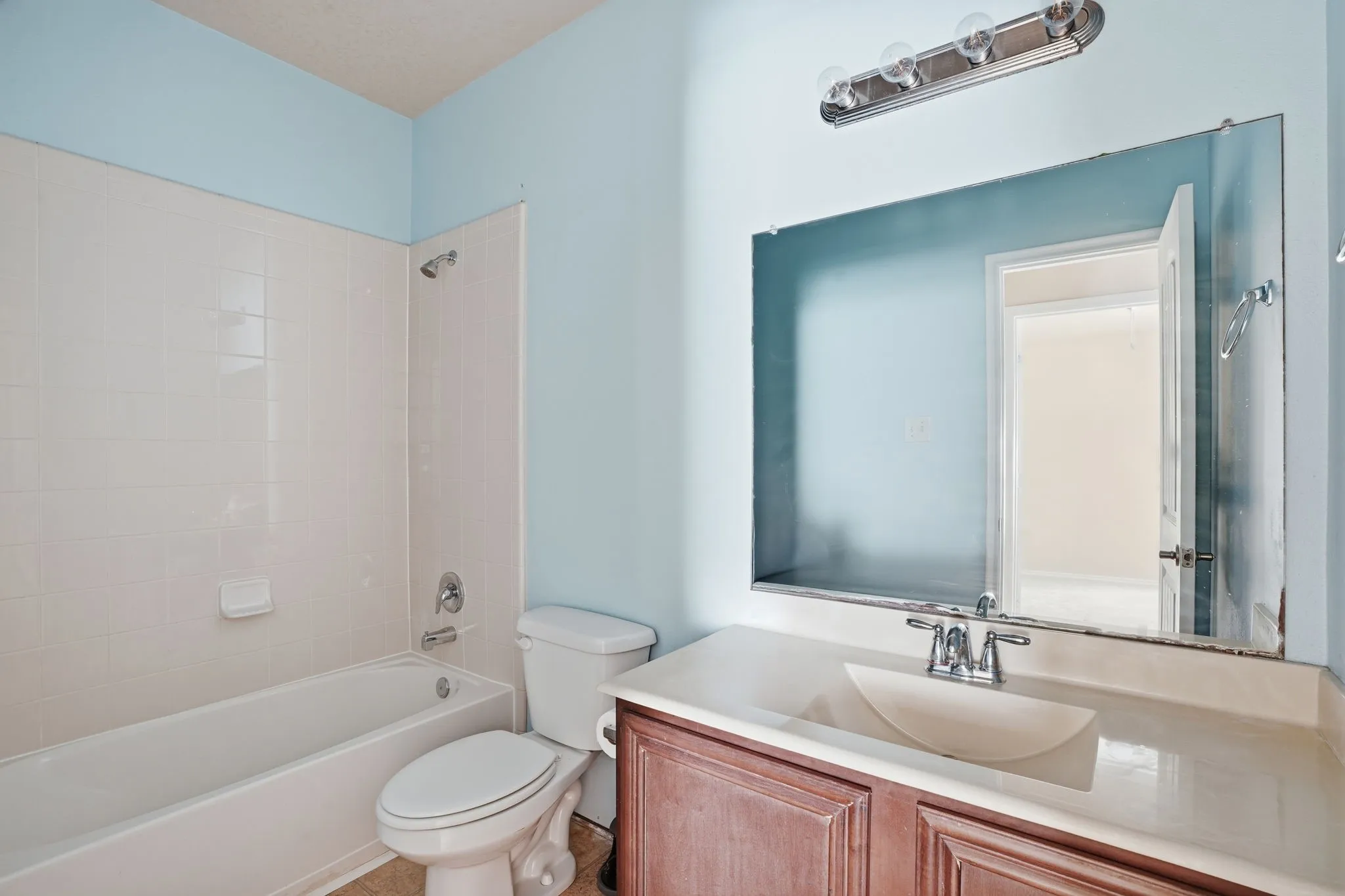 Bathroom featuring a built-in vanity with a single basin sink, chrome faucet, and a large wall-mounted mirror