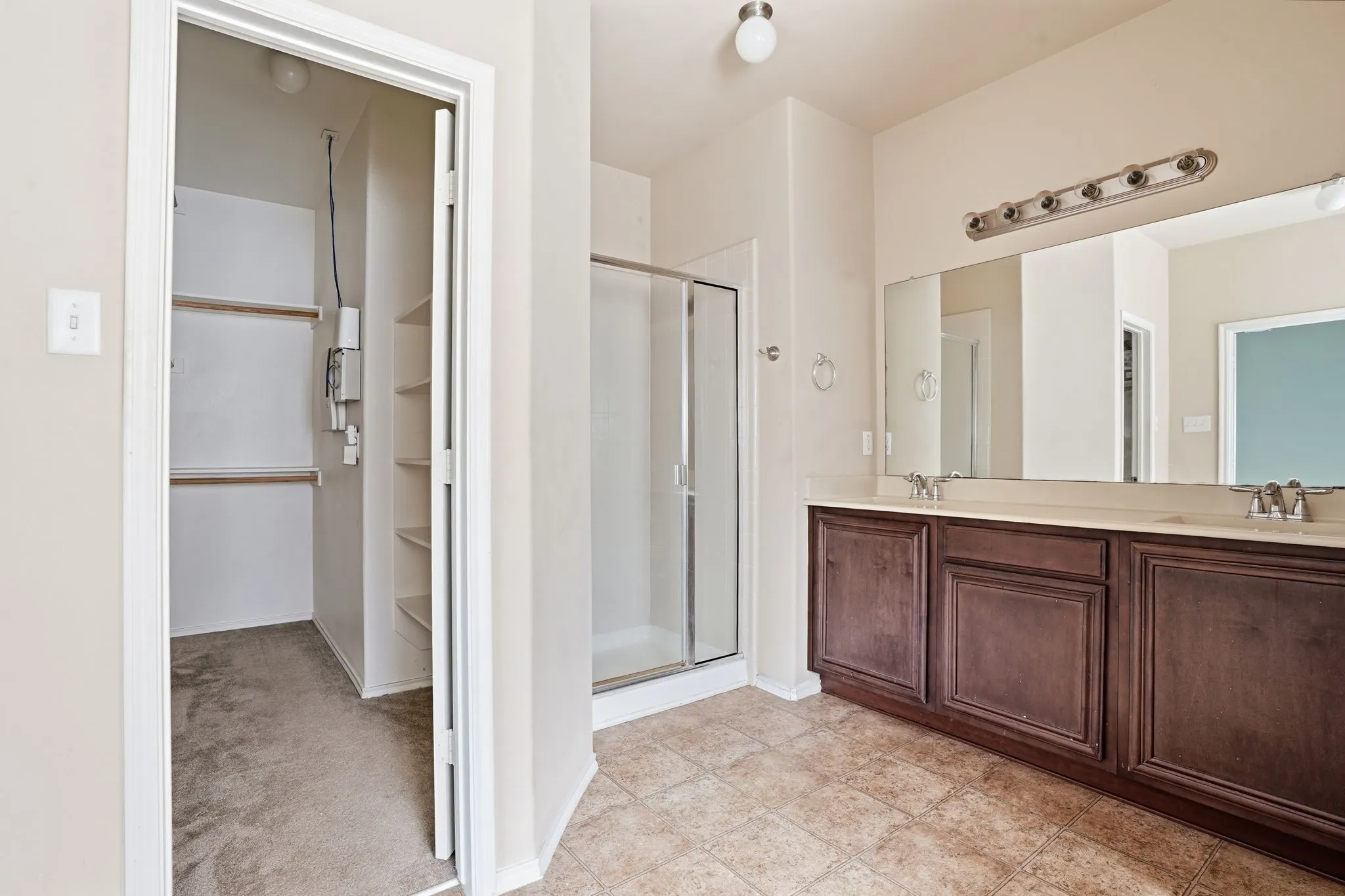 Bathroom featuring a double vanity with wood cabinetry, a light-colored countertop, and dual sinks