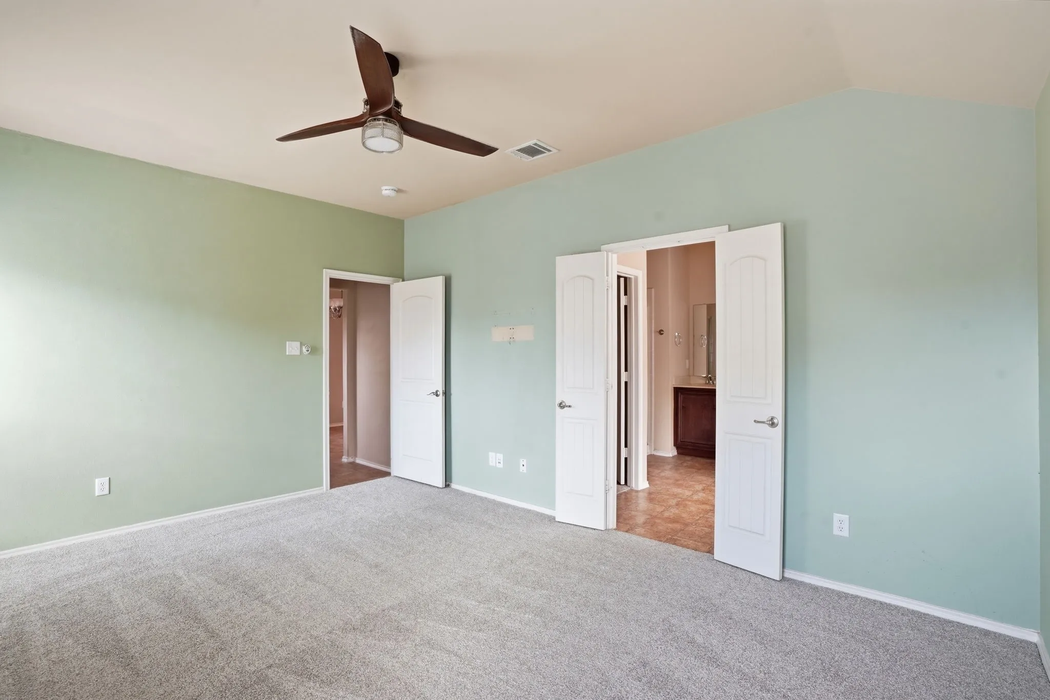 Spacious interior room featuring light green walls and plush gray carpeting