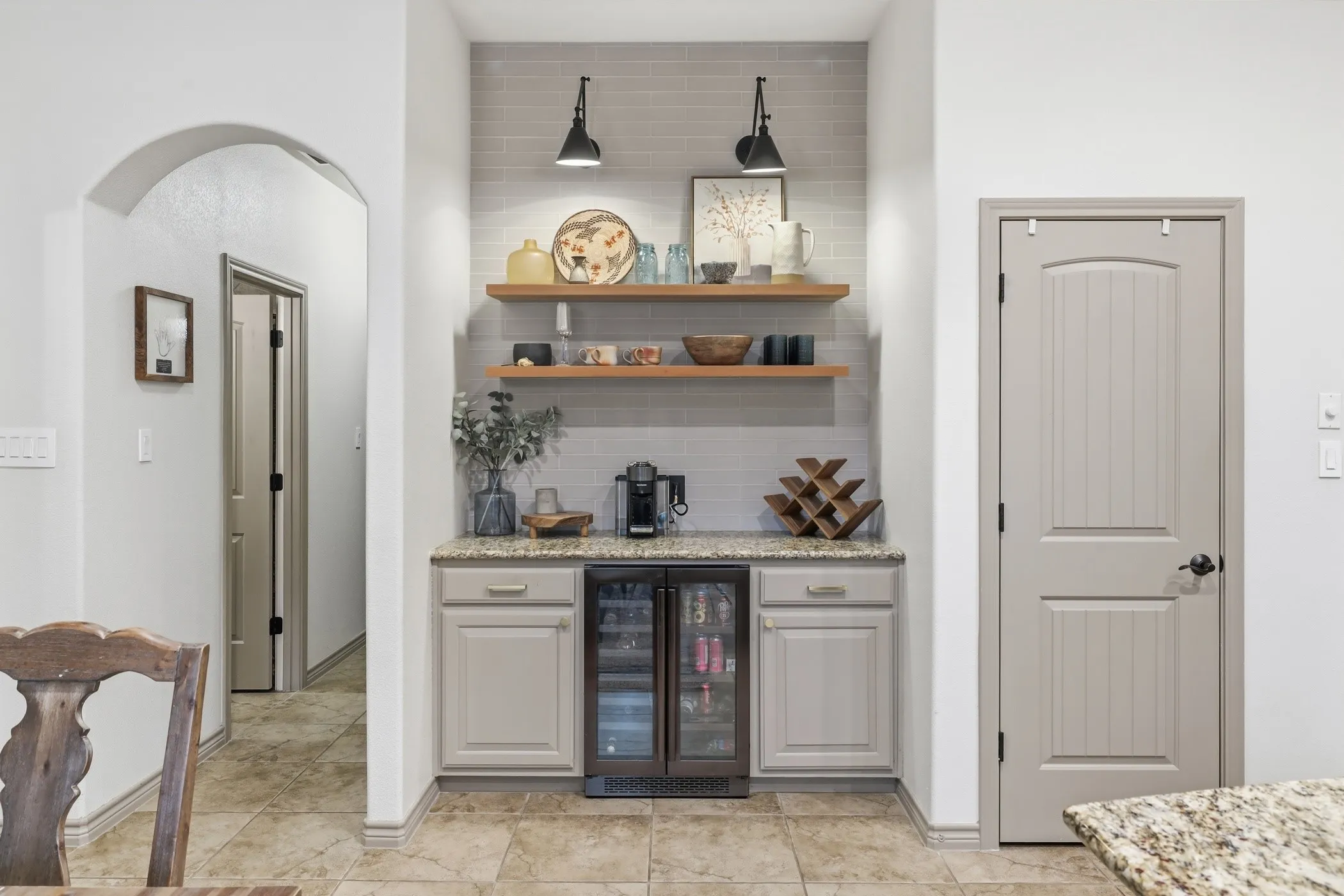 Custom bar with tile wall to ceiling, drink refrigerator, exposed wood shelves, and gorgeous lighting!