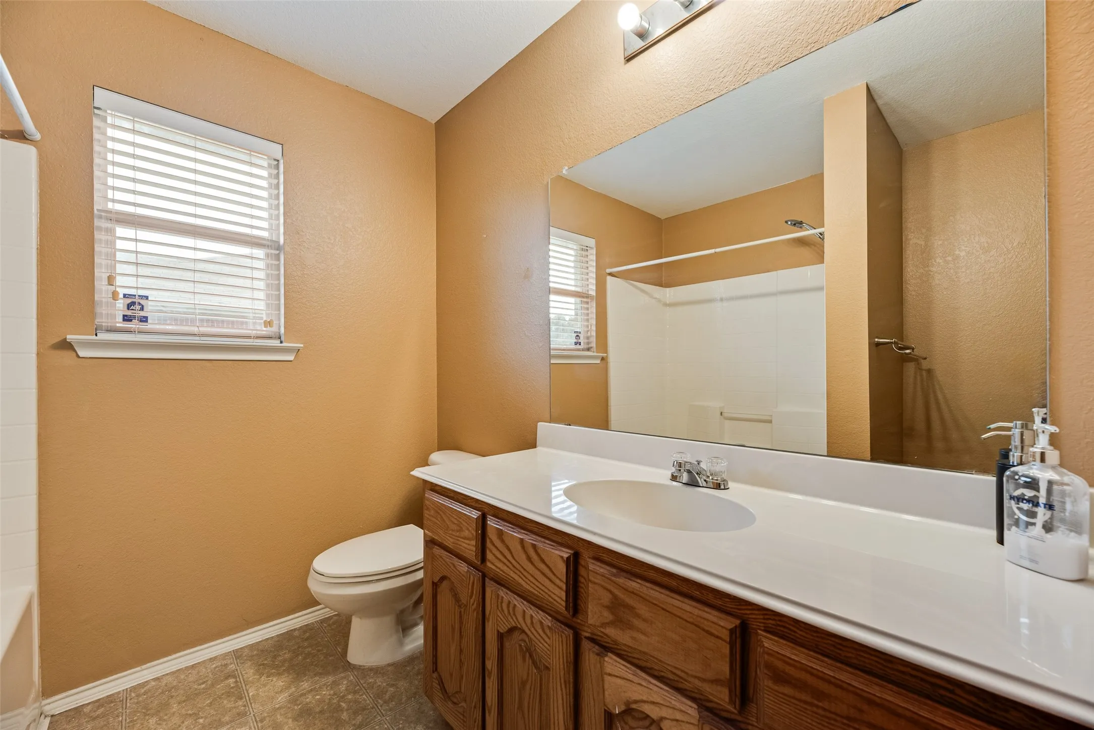 Bathroom featuring a single vanity with wood-finish cabinetry, a white countertop with an integrated sink, and a chrome faucet